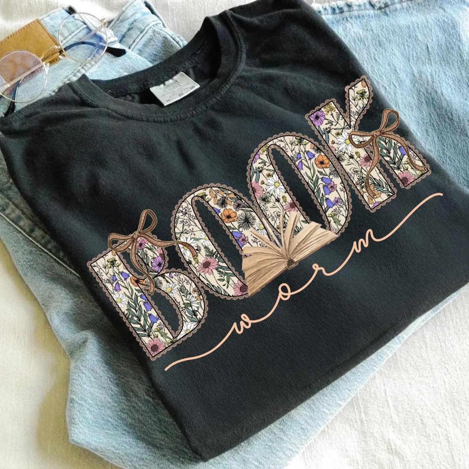 Black Book Worm graphic tee from Anchored Grace Boutique featuring a colorful worm illustration on the front.