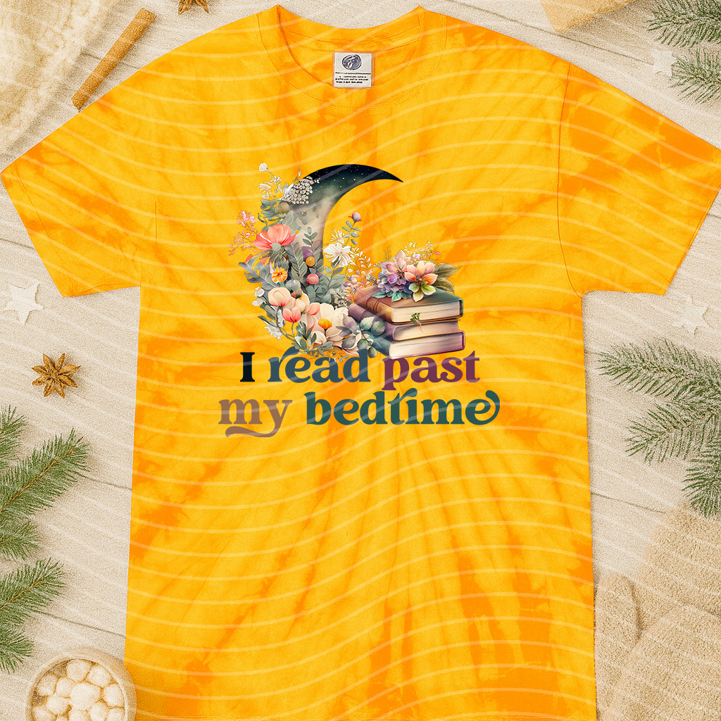 Black graphic tee with white text saying "I Read Past My Bedtime" from Anchored Grace Boutique, displayed on a hanger.