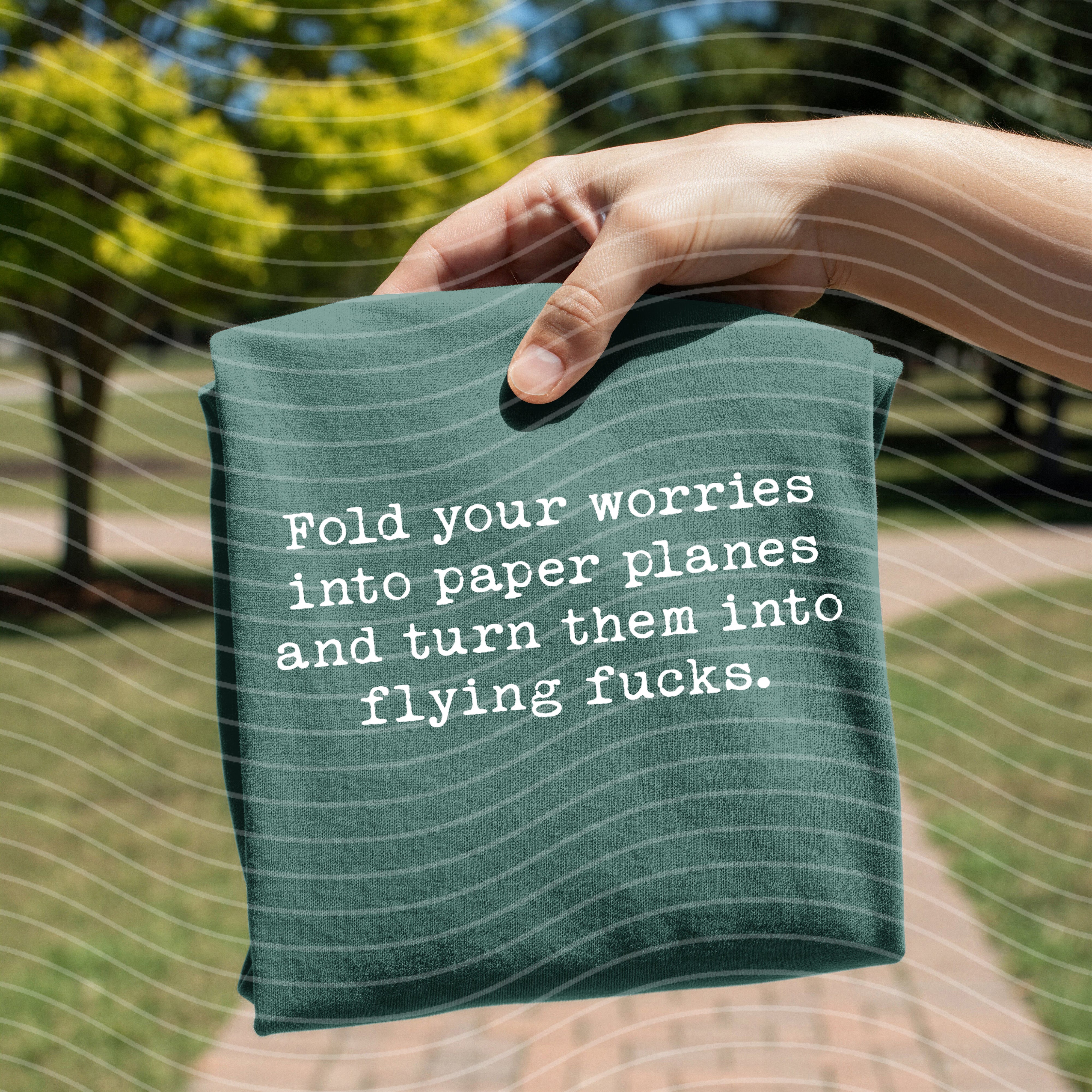 Graphic tee featuring paper planes design from Anchored Grace Boutique, casual cotton shirt with "Fold Your Worries Into Paper Planes" print.