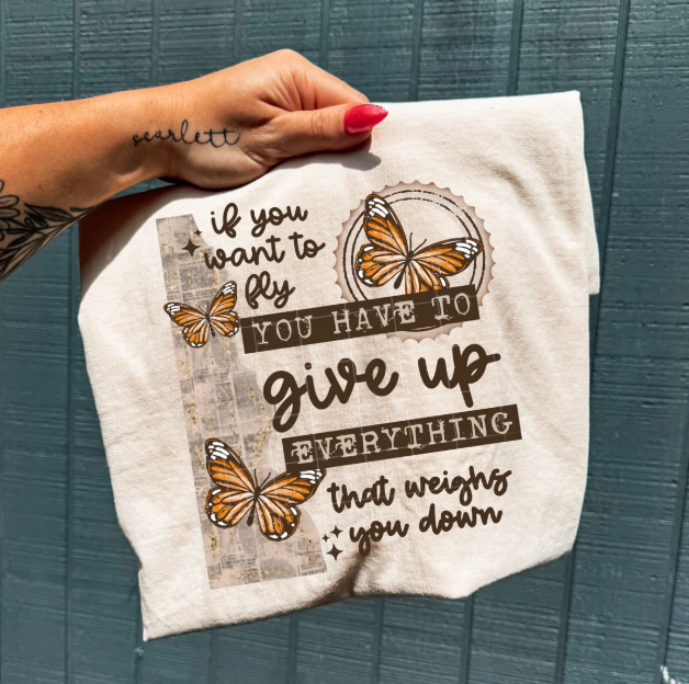 Black graphic tee from Anchored Grace Boutique with "If You Want to Fly" inspirational design and flying bird illustration.