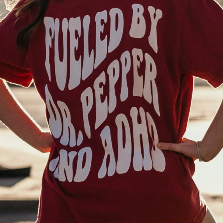 Graphic tee featuring Dr. Pepper and ADHD design from Shop Karma Tees, with vibrant colors and casual fit.