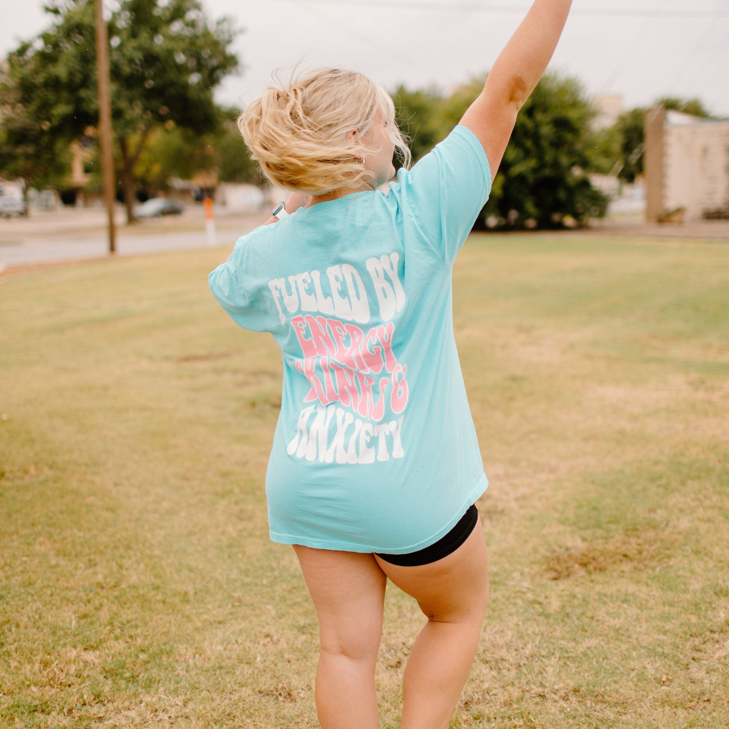 Graphic tee featuring "Fueled By Energy Drinks and Anxiety" design by Shop Karma Tees, with bold text and vibrant colors.