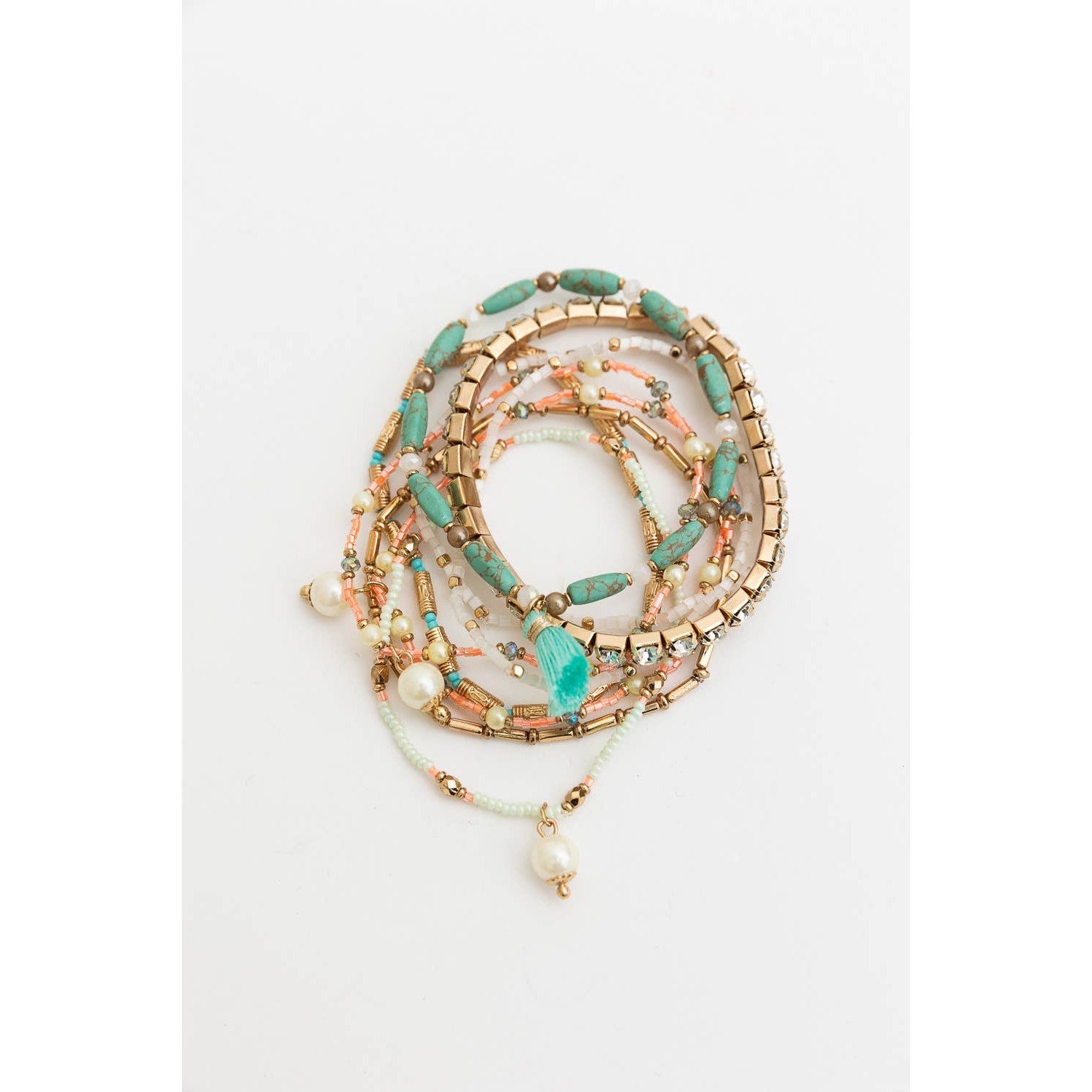 Stack of nine bohemian-inspired pastel beaded and studded bracelets with various textures and colors, perfect for layered jewelry looks.