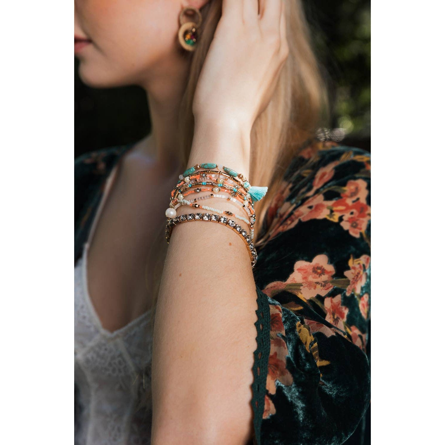 Stack of nine pastel beaded and studded bohemian-inspired bracelets with layered design, featuring colorful beads and metal studs.