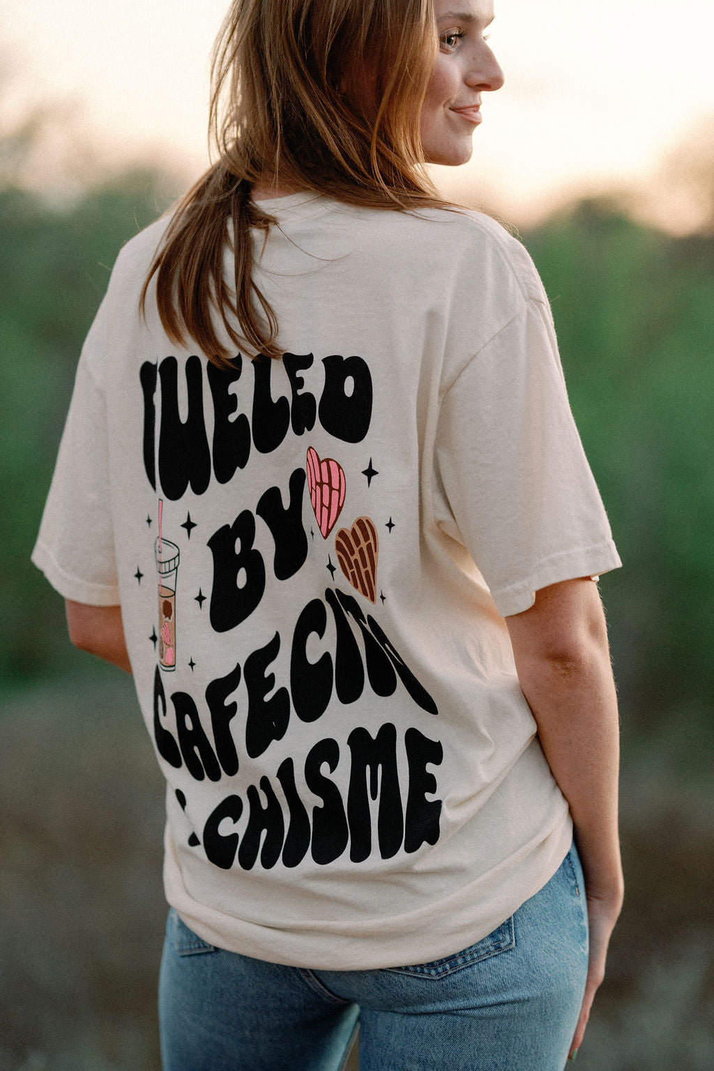 Black cotton T-shirt featuring "Fueled by Cafecito Y Chisme" slogan from Shop Karma Tees, casual fit with round neckline.