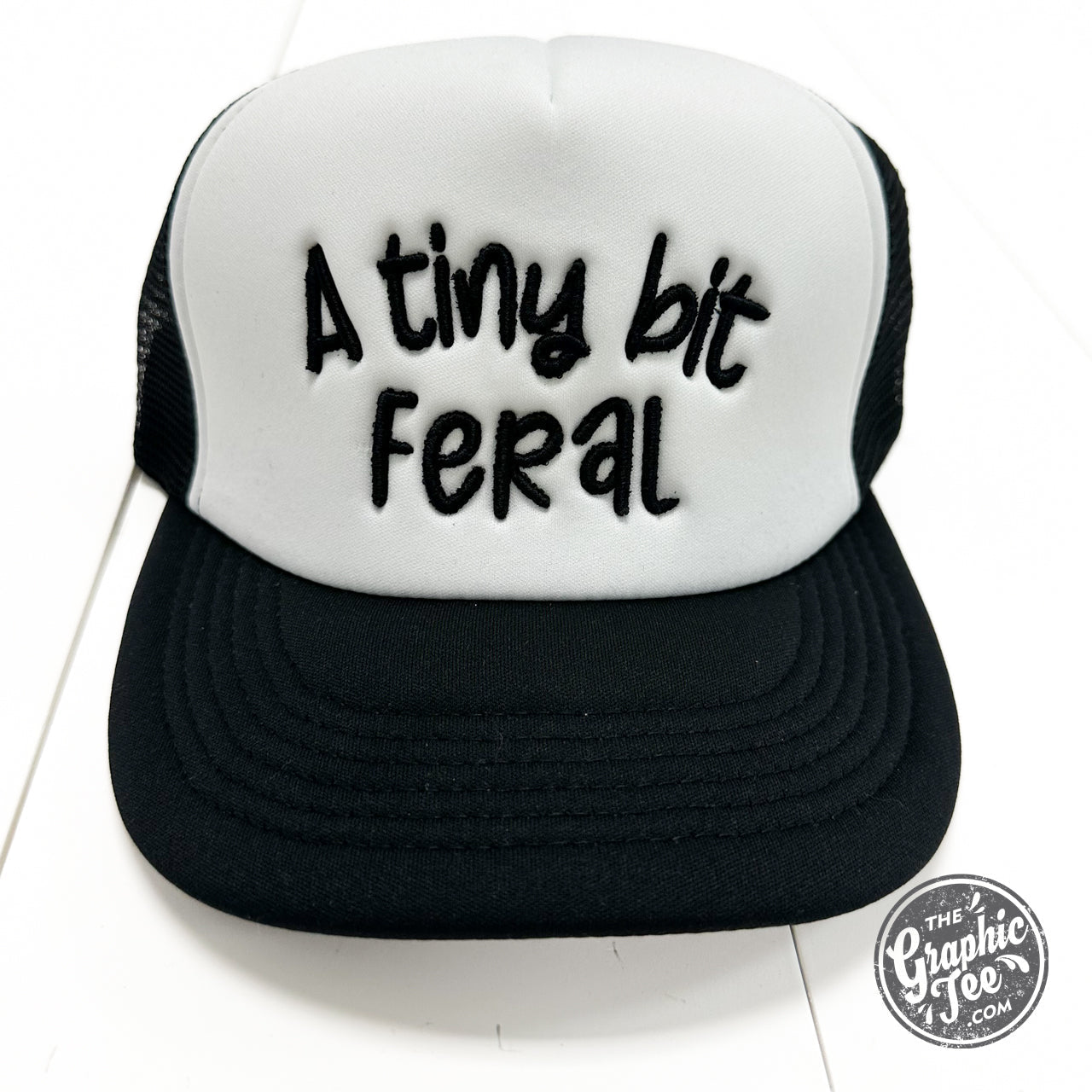 A foam trucker cap from The Graphic Tee featuring a tiny bit feral design, with mesh sides and a curved brim.