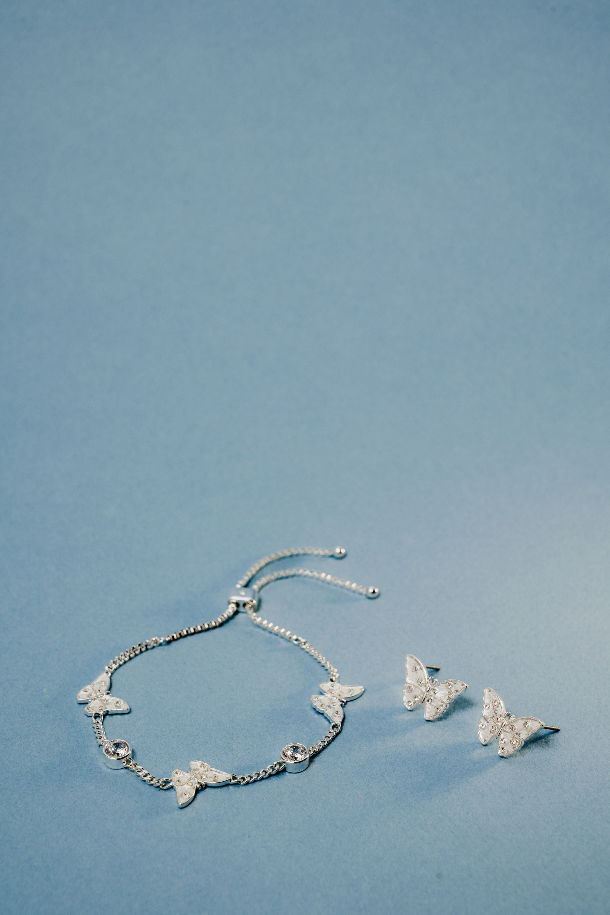 Silver glass butterfly statement stud earrings by ALEX AND ANI, featuring intricate butterfly designs on shiny metal posts.