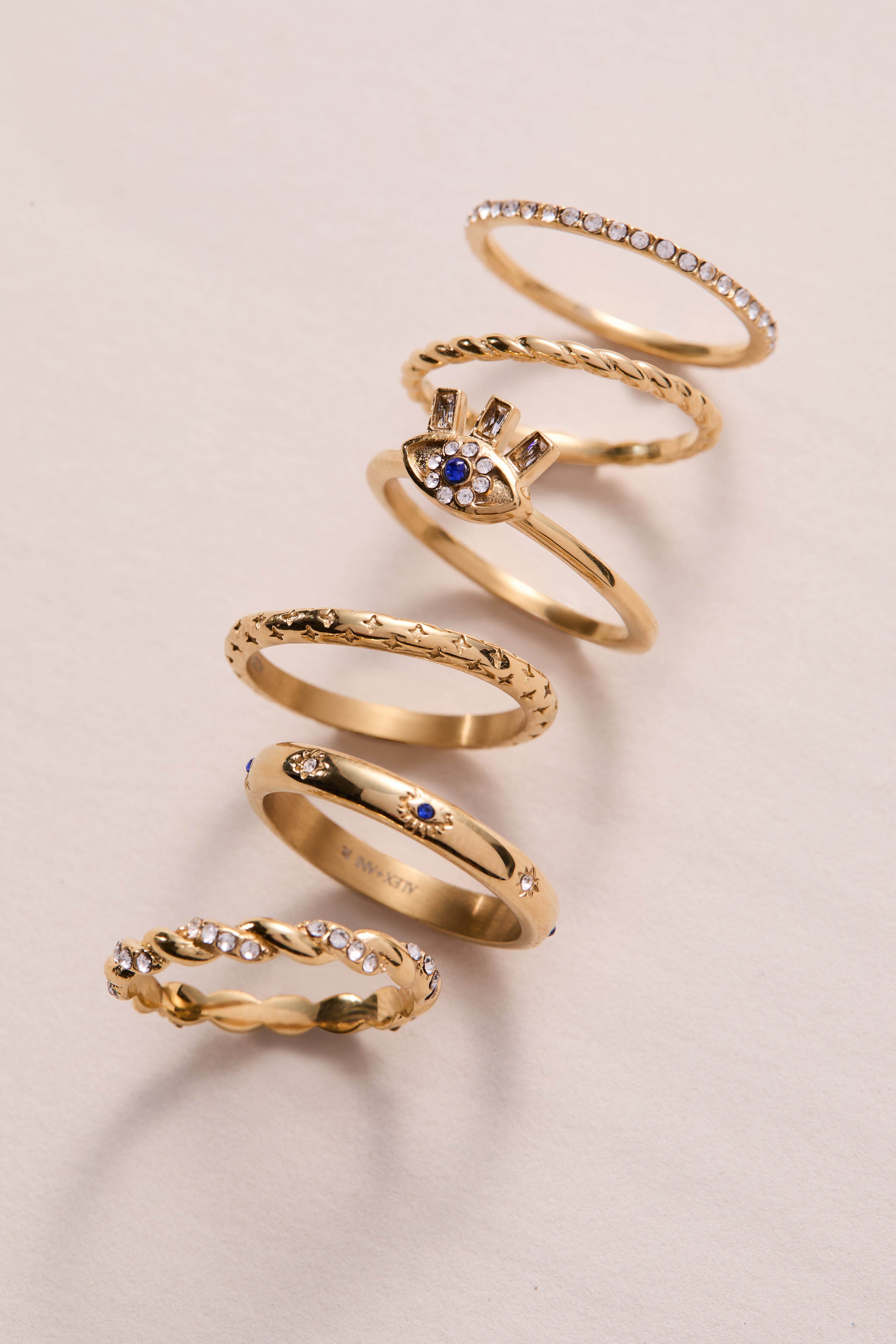 Set of three gold stainless steel Evil Eye stacking rings by ALEX AND ANI, featuring protective eye motifs and sleek design.