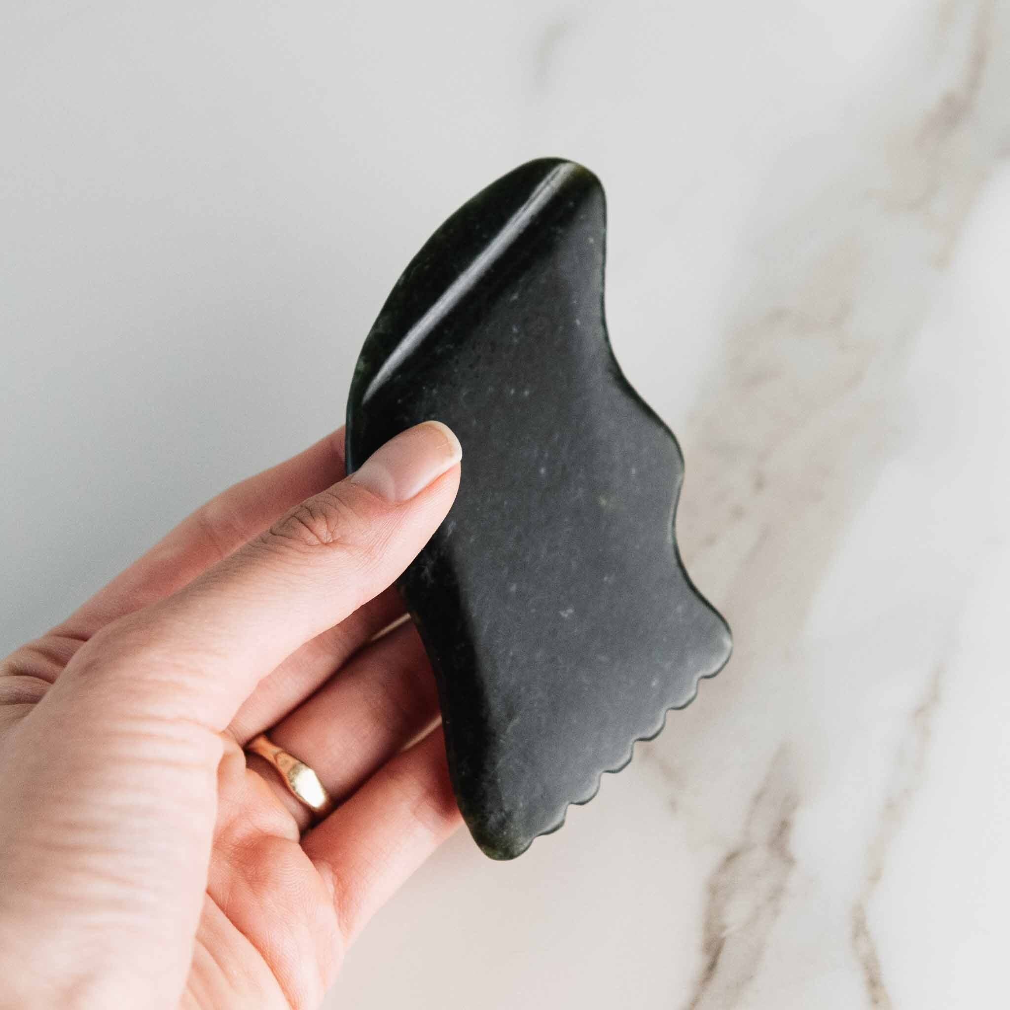 Black nephrite Gua Sha lifting tool by Annmarie Skin Care, used for facial massage and skincare routines.