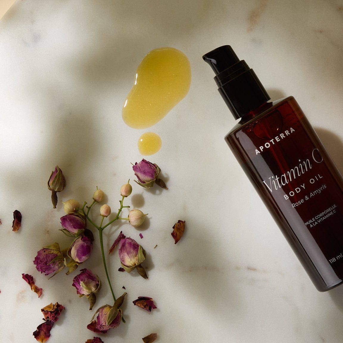 Apoterra Vitamin C Body Oil with rose and amyris, showing a textured, amber-colored oil in a glass bottle for bath and body use.