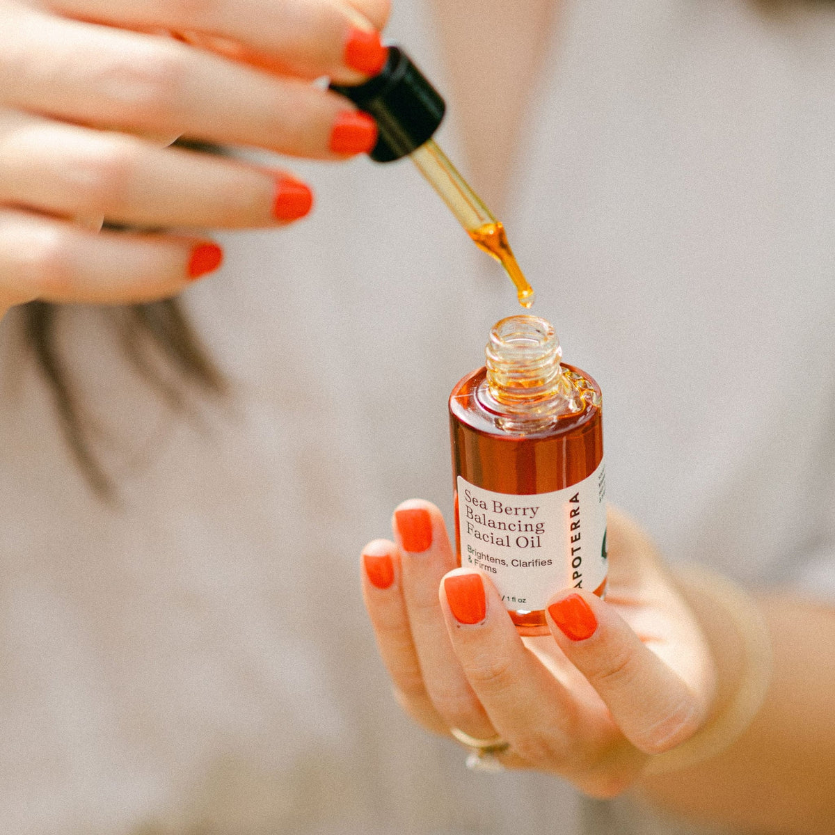 Apoterra Sea Berry Balancing Facial Oil dropper held in hand, showcasing natural facial oil for skin nourishment and balance.