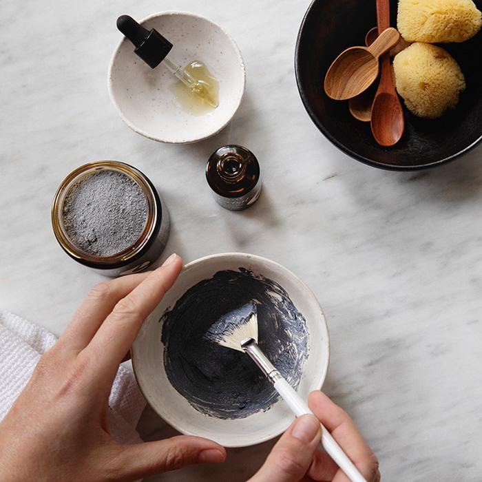 Apoterra Mineral Purifying Mask treatment being mixed in a bowl with charcoal and clay for deep cleansing skincare.