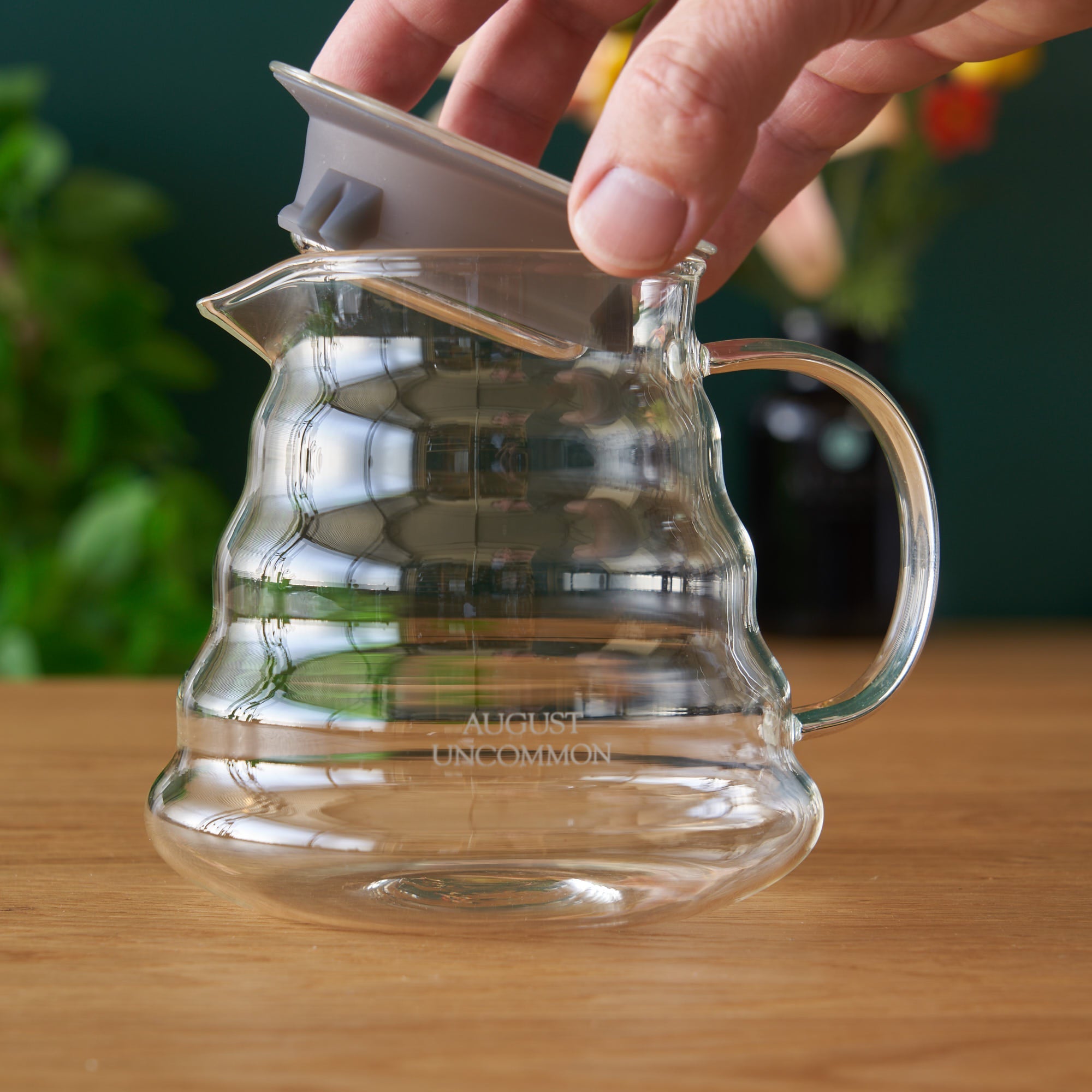Two Cup Glass Teapot by August Uncommon Tea showing clear glass body, handle, spout, and lid for brewing tea.