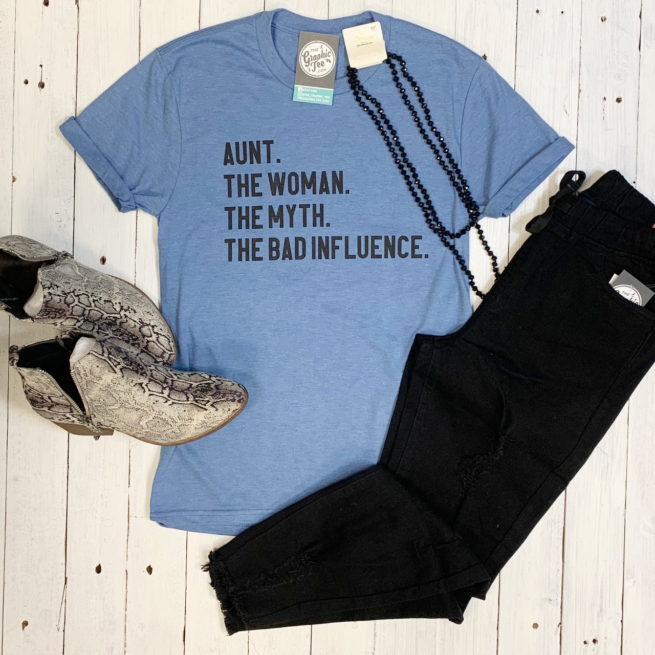 Bright white SS graphic tee from The Graphic Tee featuring bold text: "Aunt. The Woman. The Myth. The Bad Influence."