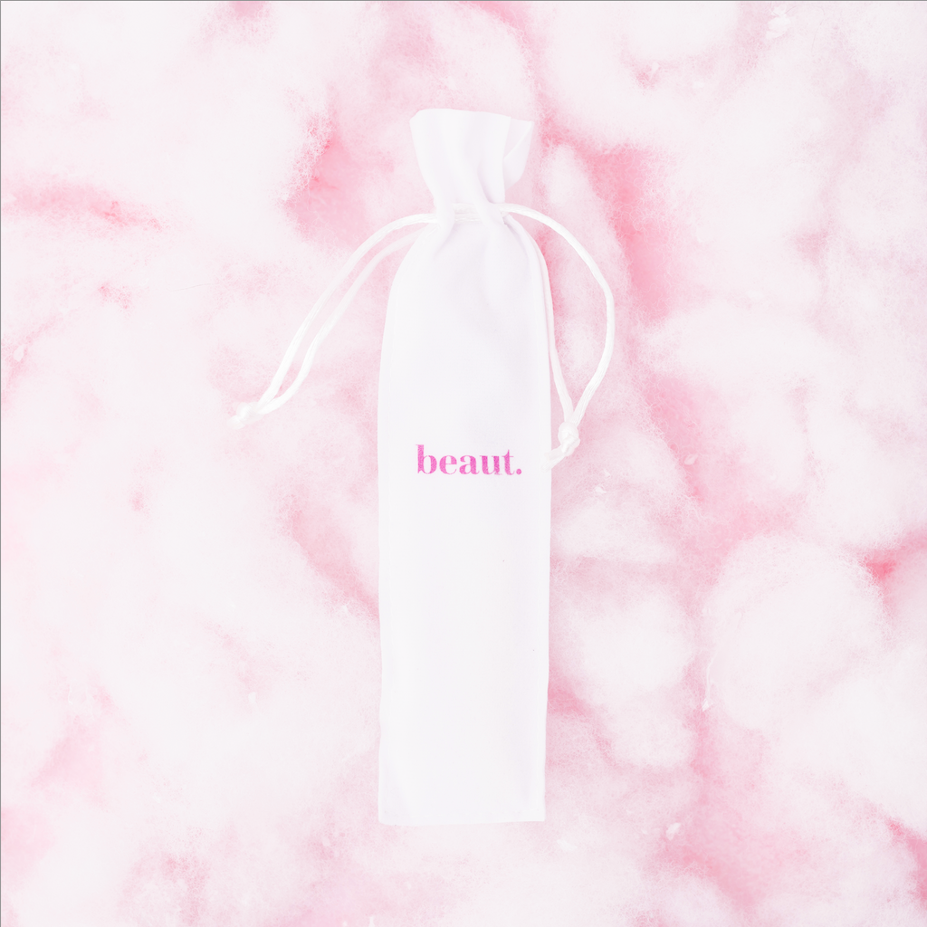 Pink tongue scraper from beaut.beautyco., with a smooth handle and curved scraping surface for oral hygiene.