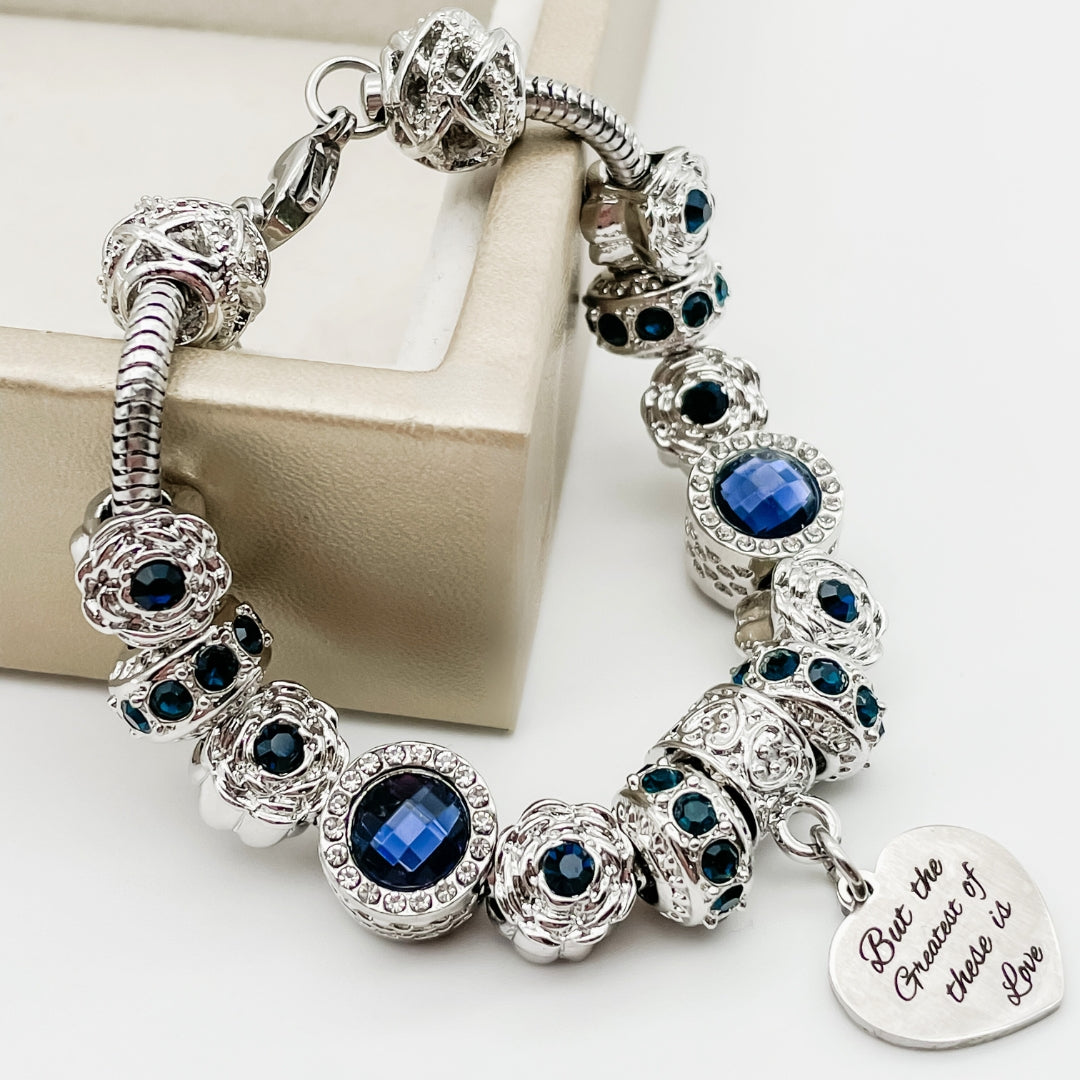 Close-up of Bella's Yard Faith Hope Love bracelet featuring engraved metal charms on a delicate chain.