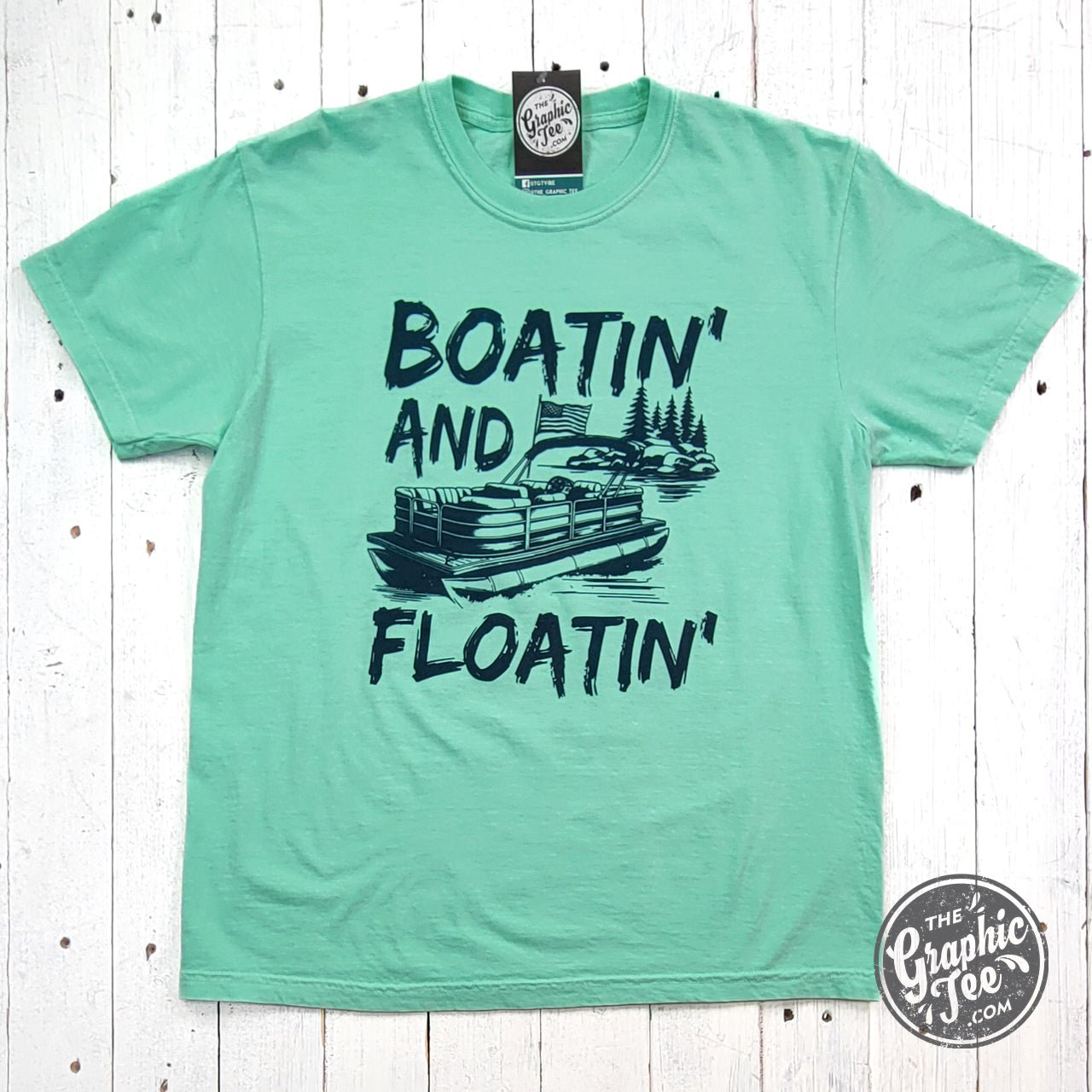 Blue pigment-dyed Boatin' and Floatin' graphic tee by The Graphic Tee, showcasing boat and float images on a casual short-sleeve shirt.