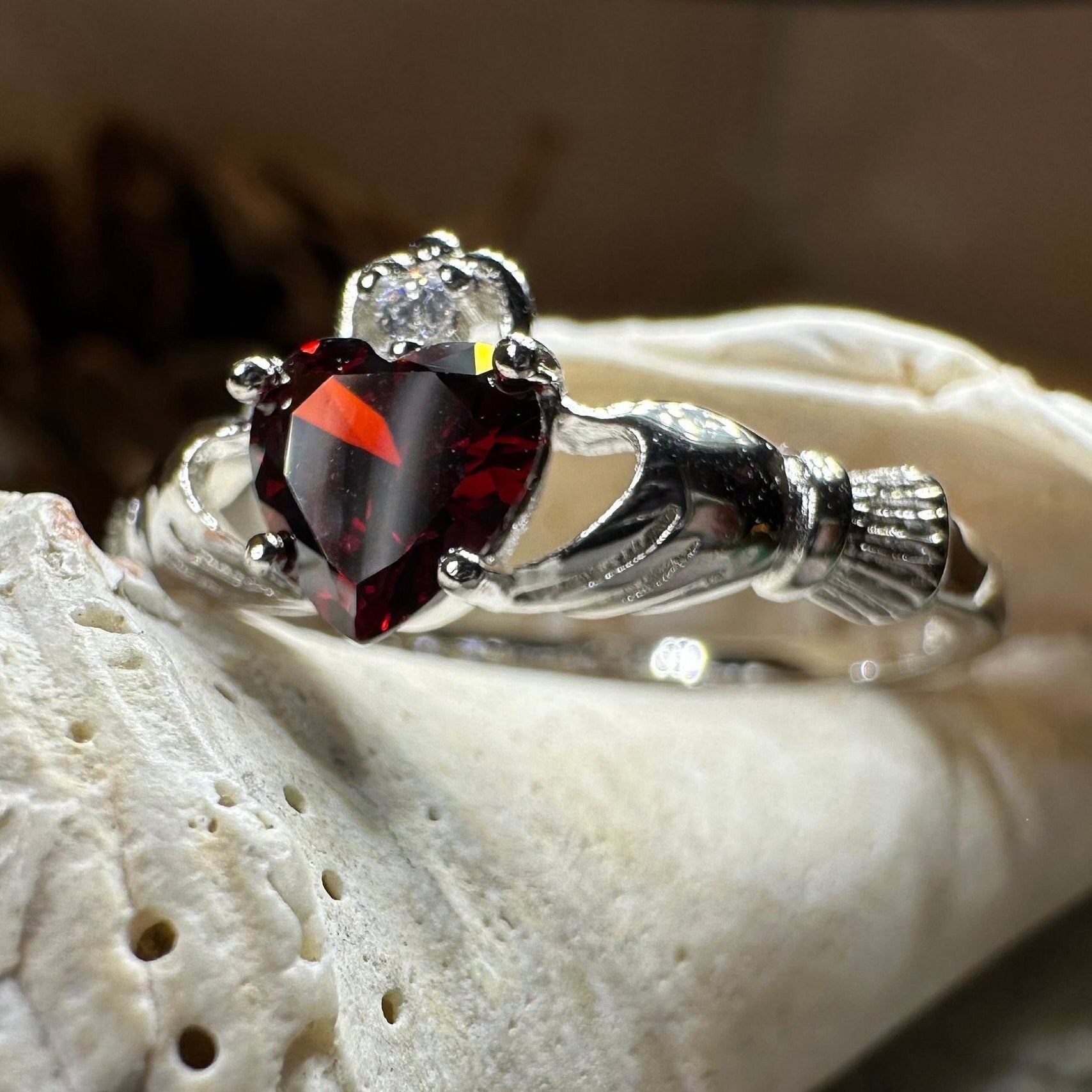 Celtic Crystal Design Jewelry Garnet Claddagh ring with intricate Celtic knot detailing and a central garnet gemstone.