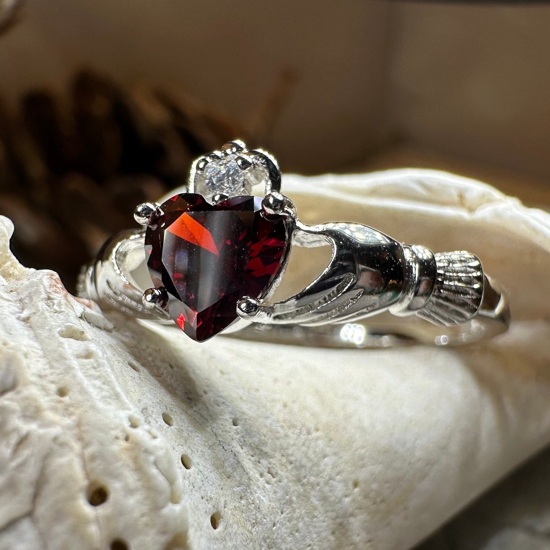 Celtic Crystal Design Jewelry garnet Claddagh ring with detailed Celtic knots and a central red garnet gemstone.