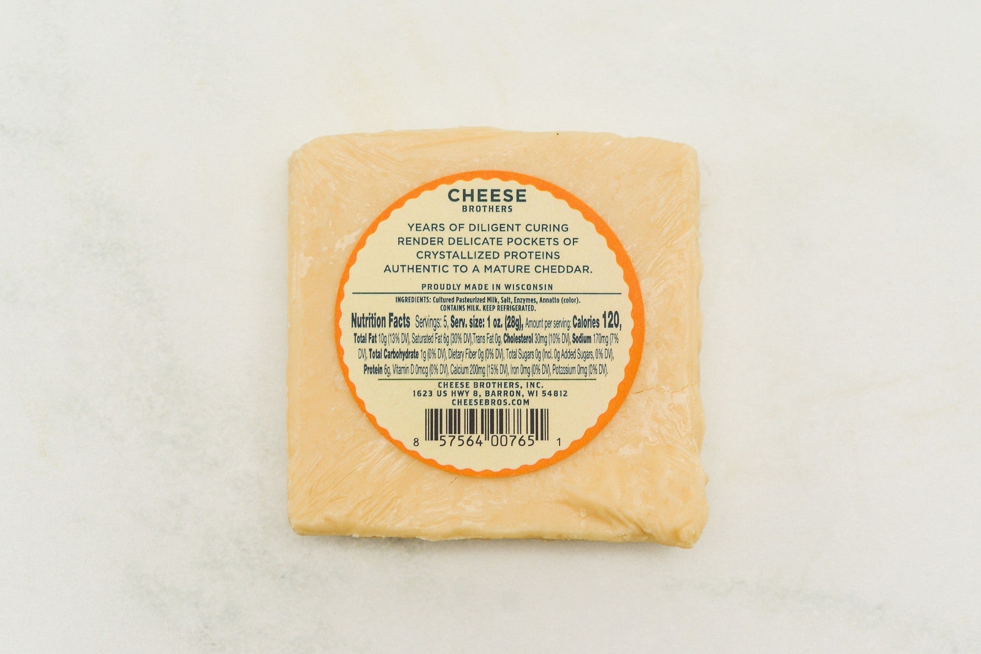 A wedge of 15-year-aged cheddar cheese from Cheese Brothers, Inc., showing its firm texture and rich, golden color.
