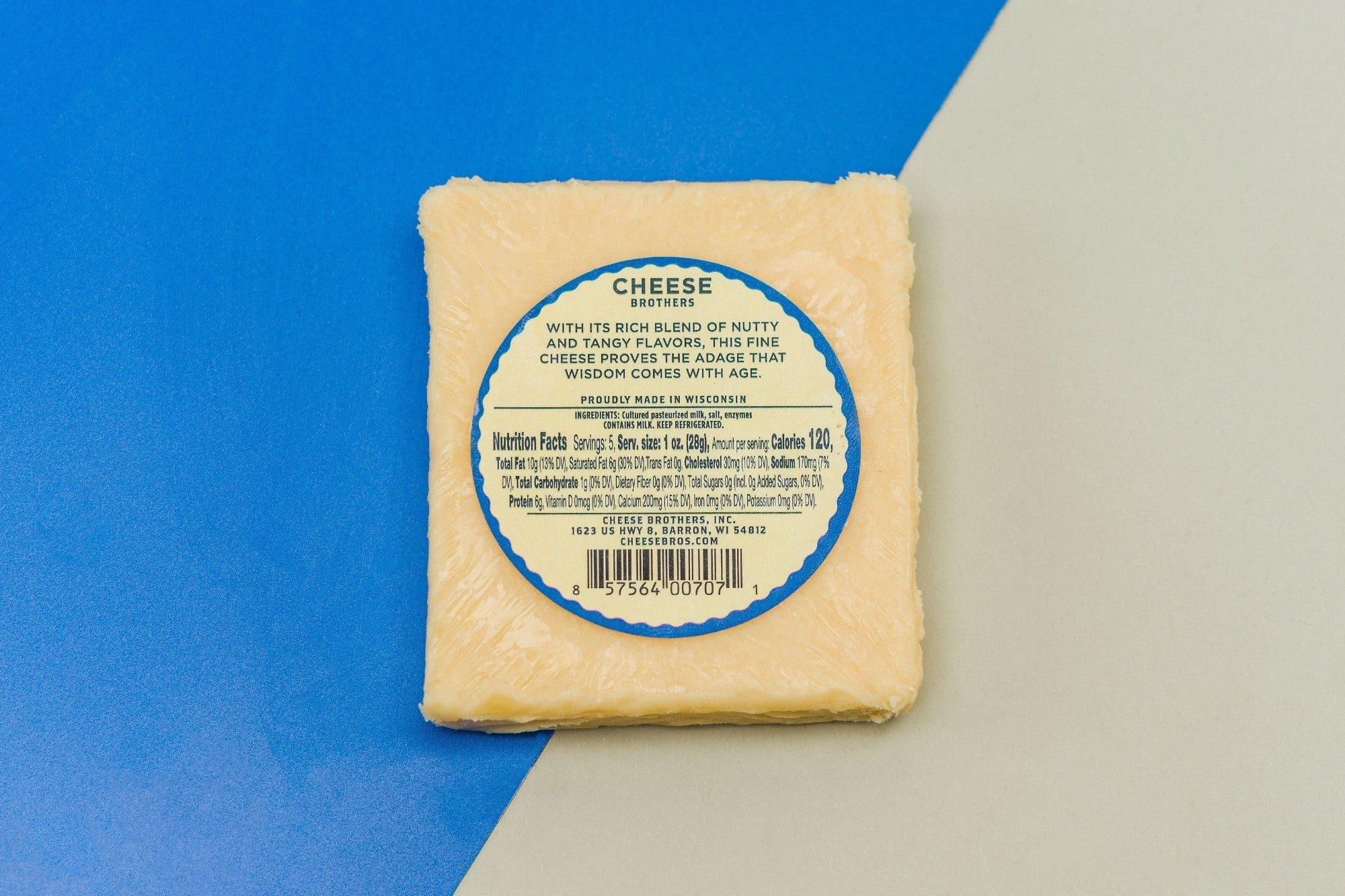 A block of 8-year-aged cheddar cheese from Cheese Brothers, Inc., showcasing its firm texture and rich, yellow color.