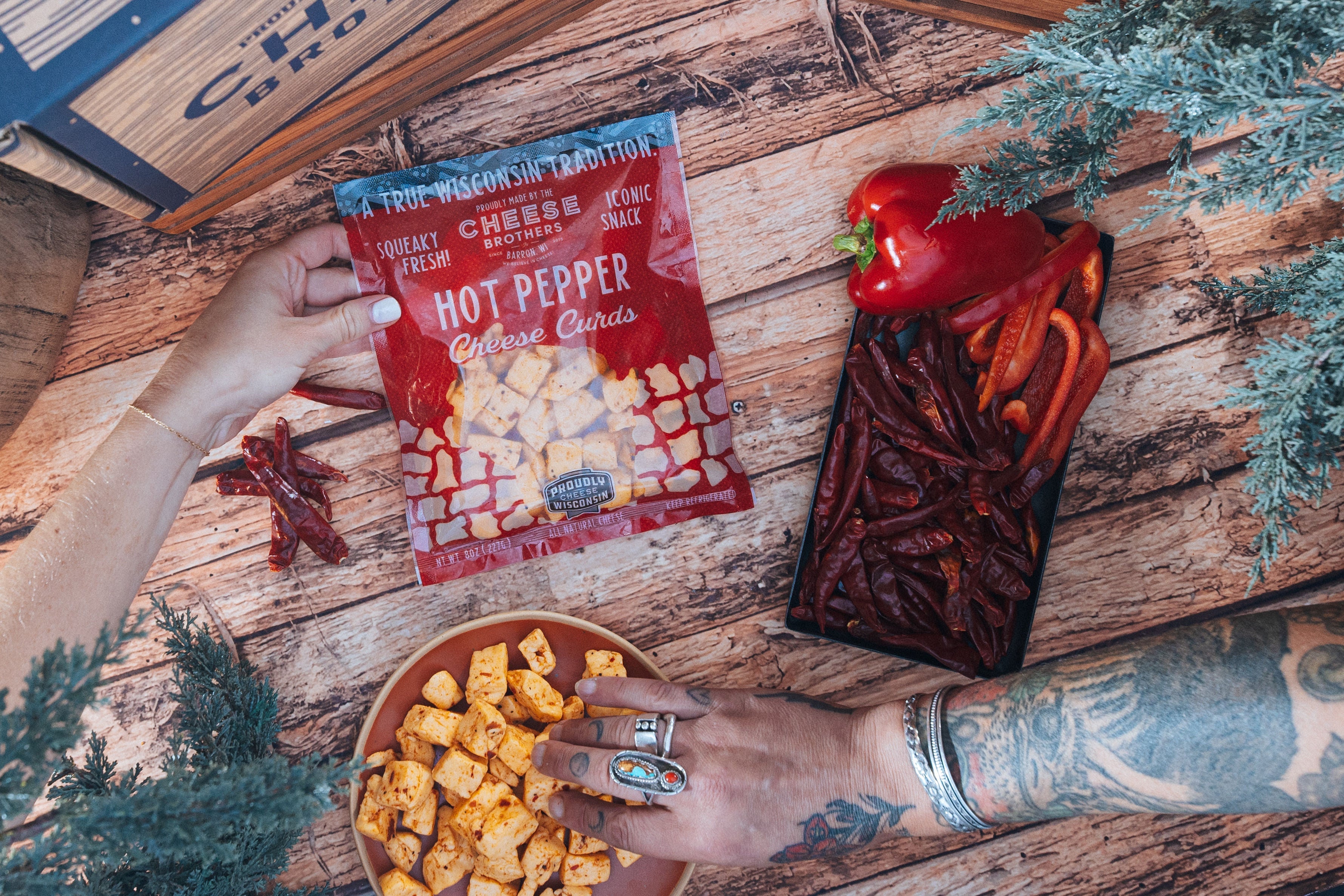Cheese Brothers Inc. hot pepper cheese curds, freshly shipped, showing vibrant orange cheese curds with hot pepper bits in a clear container.