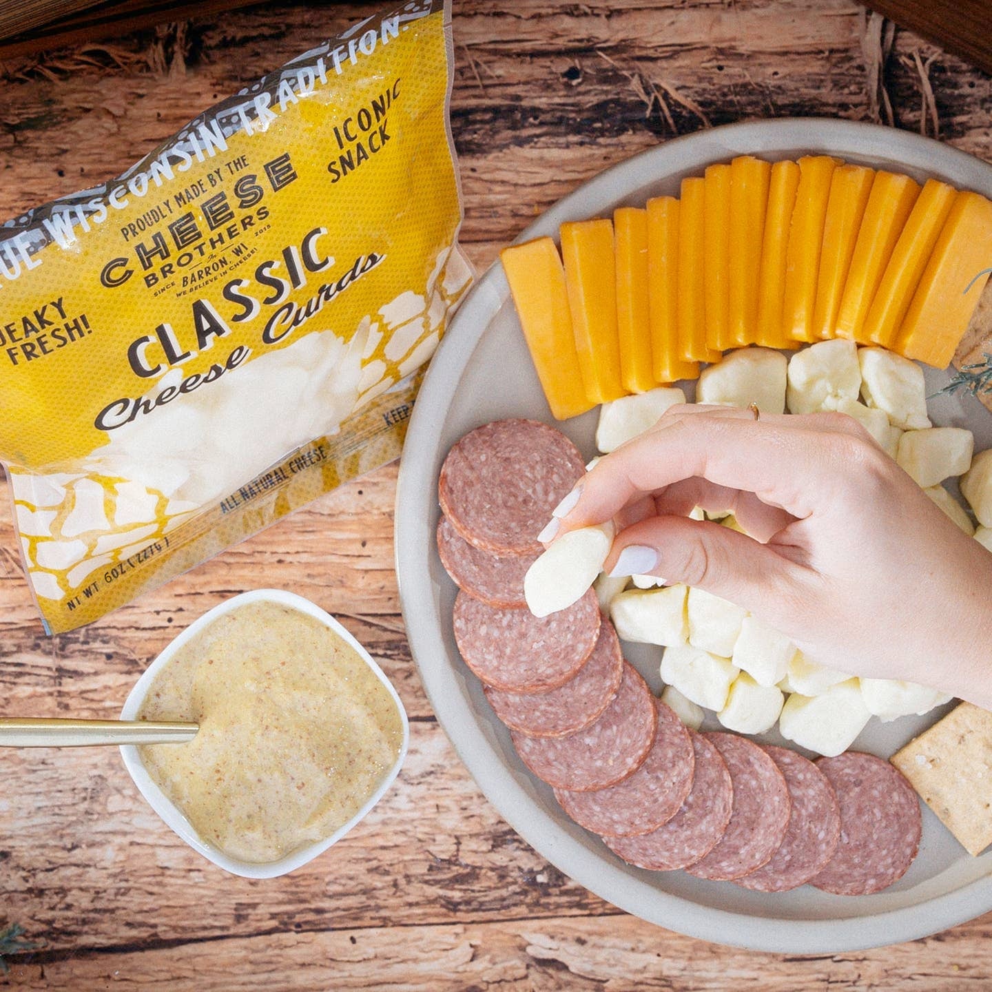 Fresh Wisconsin Cheese Curds by Cheese Brothers, Inc., showing golden, lightly fried cheese curds on a rustic plate.