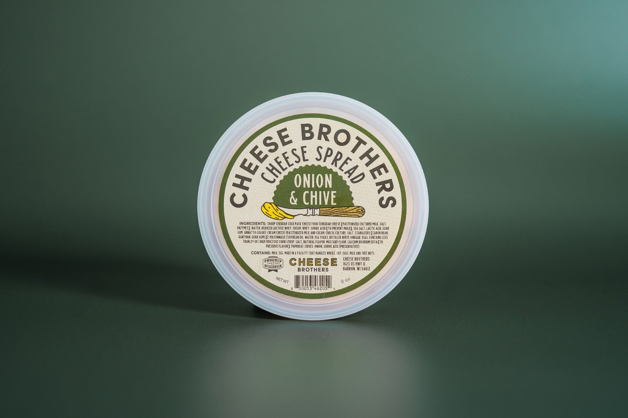 Creamy onion and chive cheese spread by Cheese Brothers, Inc. in a jar with fresh herbs visible, perfect for spreading or dipping.
