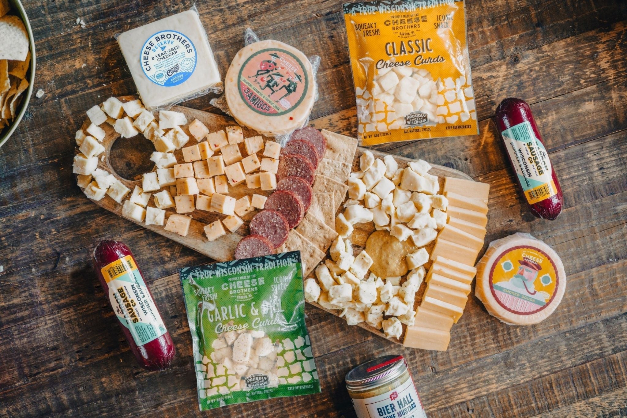 Cheese Brothers, Inc. Deluxe Game Day Essentials Gift Pack with snacks, drinks, and game day accessories in a festive box.