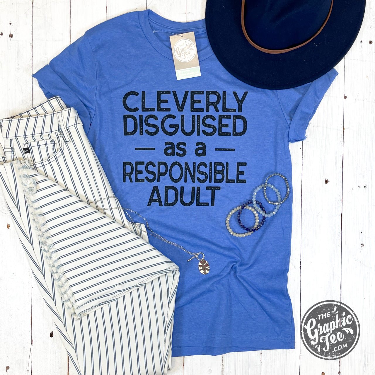 A black SS graphic tee by The Graphic Tee featuring humorous text that reads "Cleverly Disguised as a Responsible Adult."
