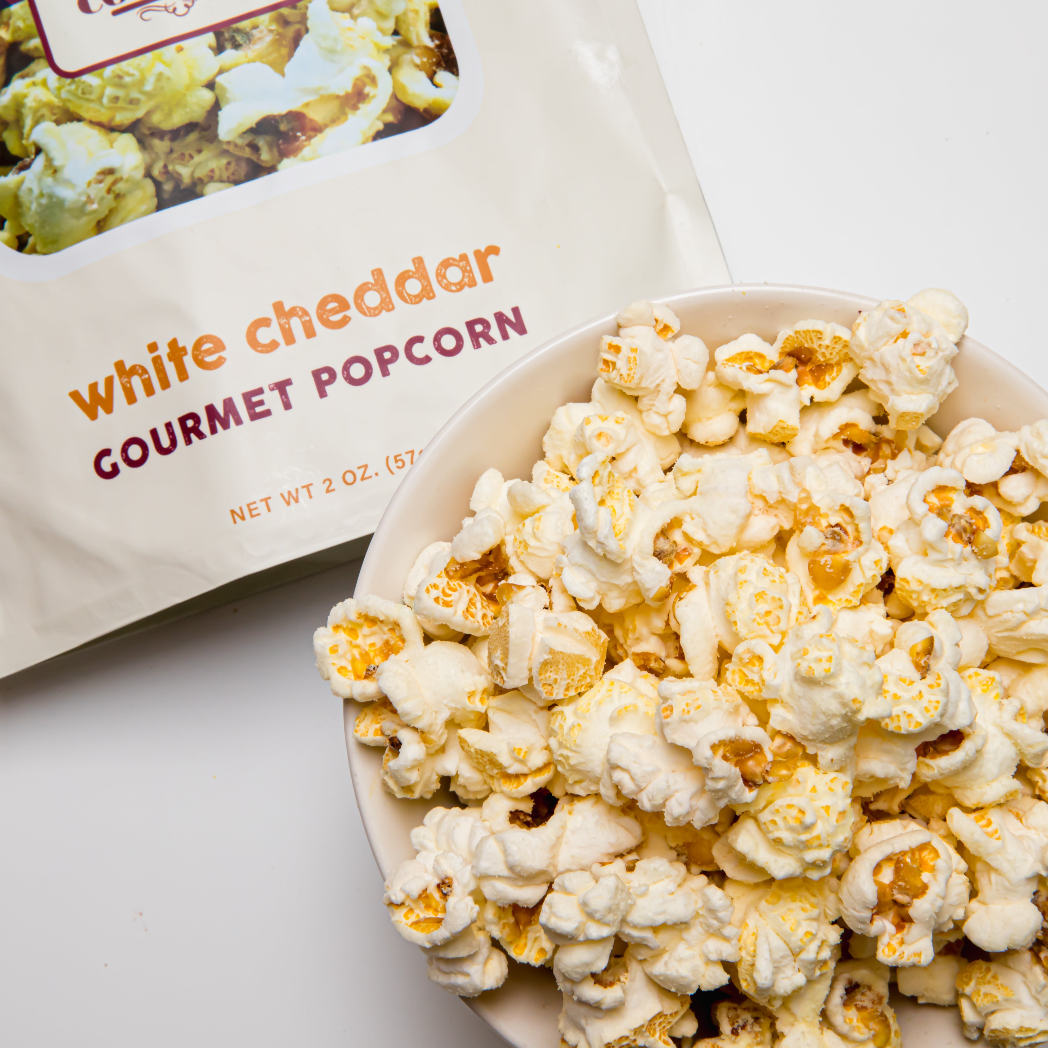 White cheddar popcorn from Colorado Popcorn Company in a 2 oz bag, showing crunchy popcorn coated with creamy white cheddar.