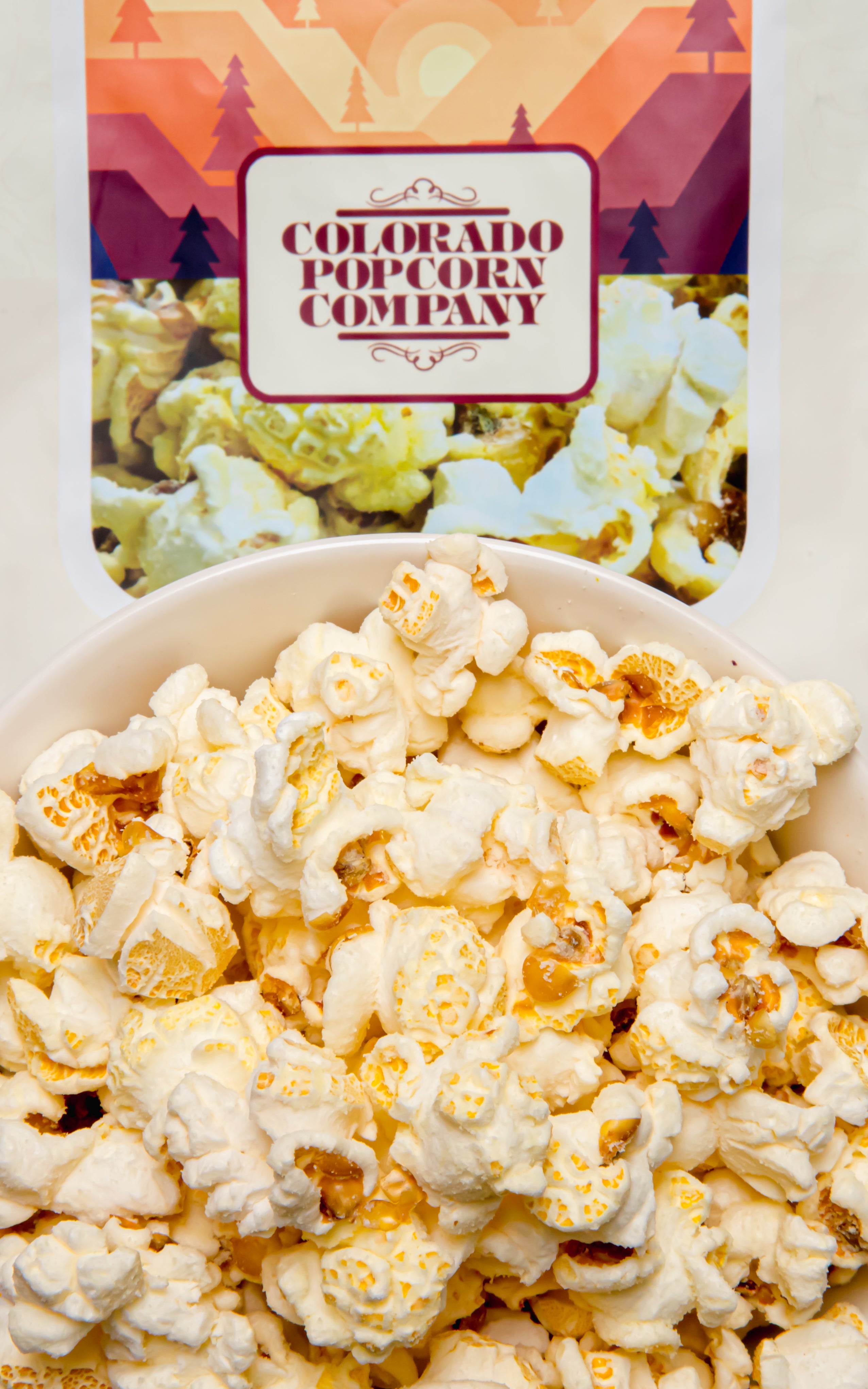 White cheddar popcorn in a clear bag from Colorado Popcorn Company, featuring crispy, cheesy popcorn pieces.