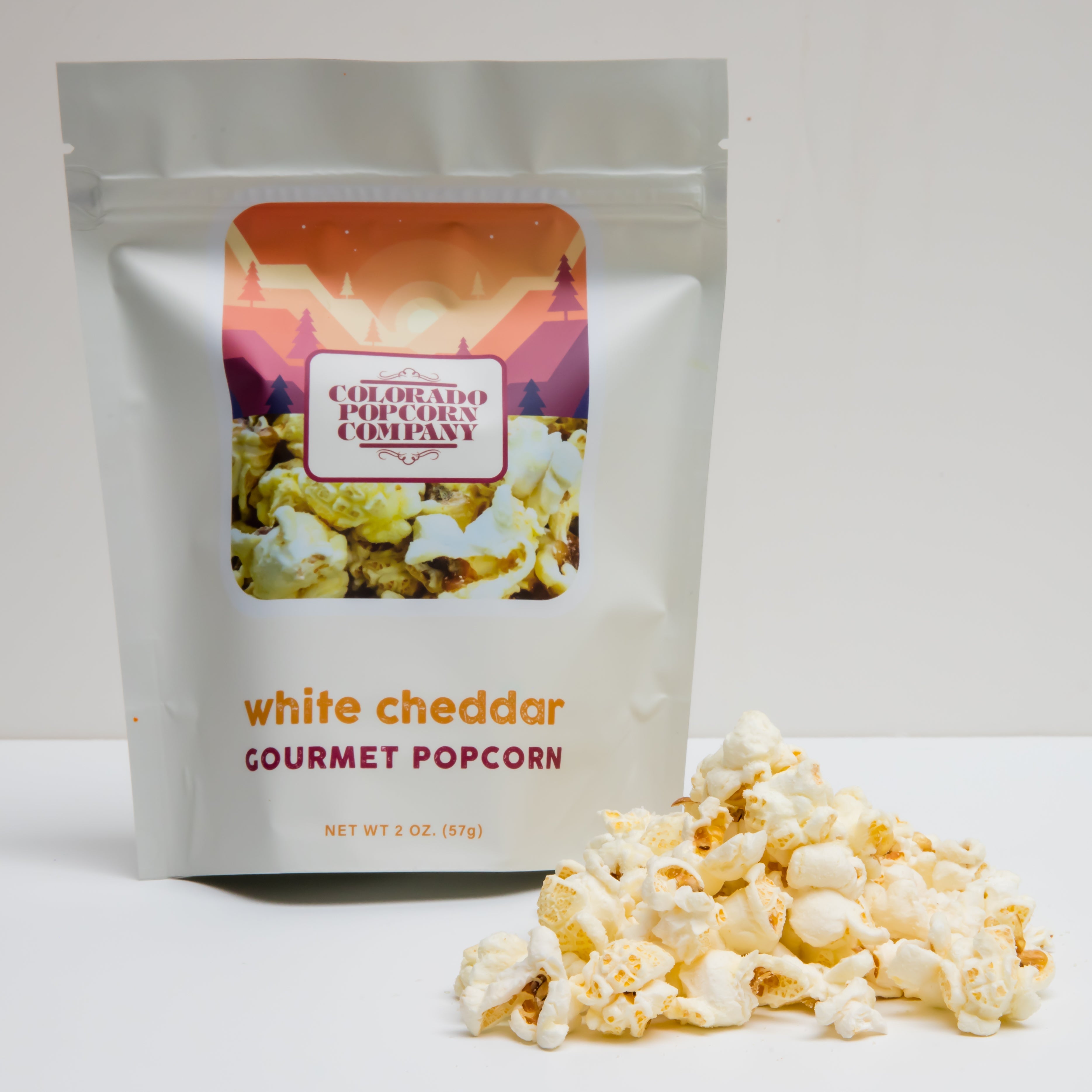 White cheddar popcorn from Colorado Popcorn Company in a 2 oz bag, showing crunchy popcorn coated with white cheddar cheese.