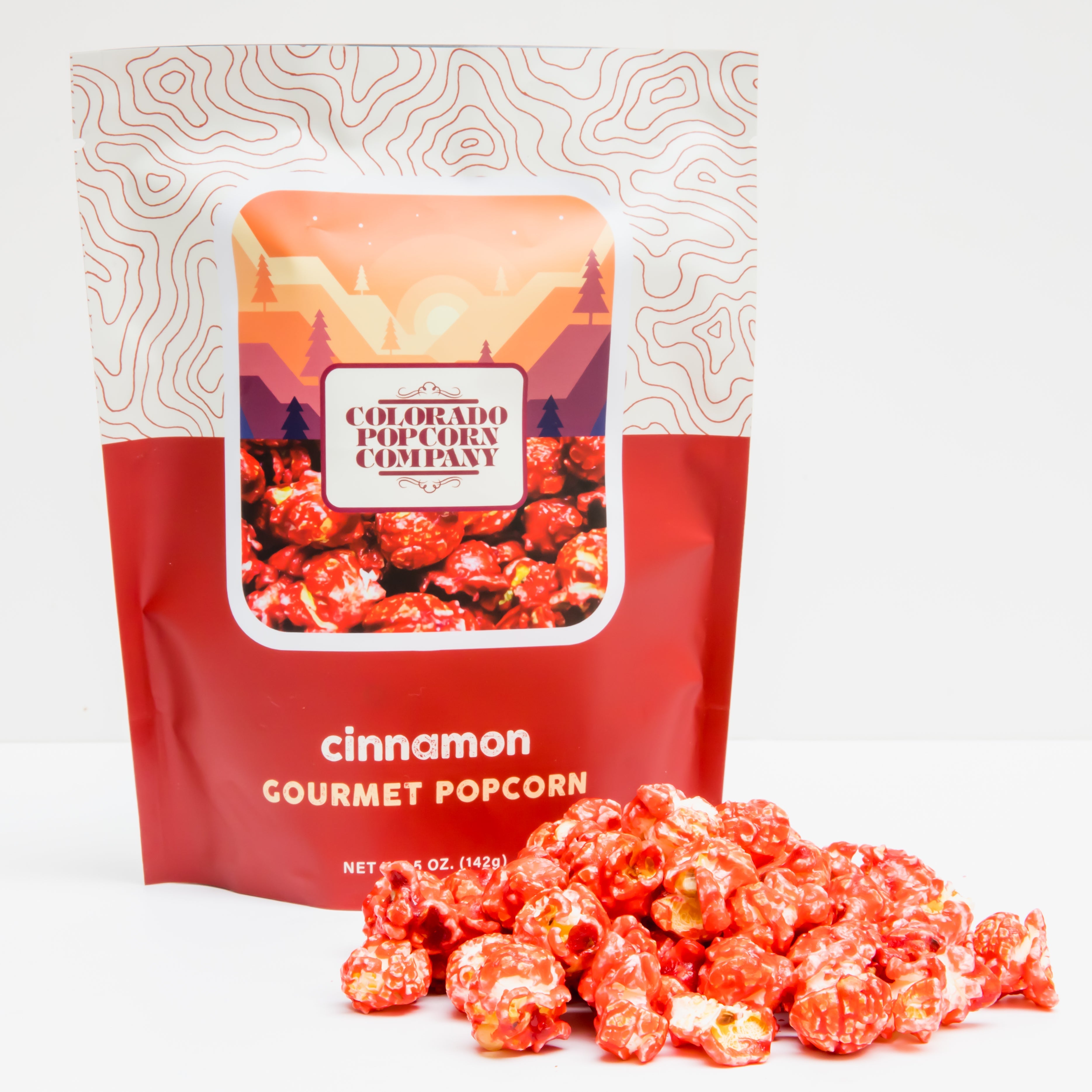 Cinnamon popcorn in a clear bag from Colorado Popcorn Company, 5 oz net weight, with cinnamon-coated kernels inside.