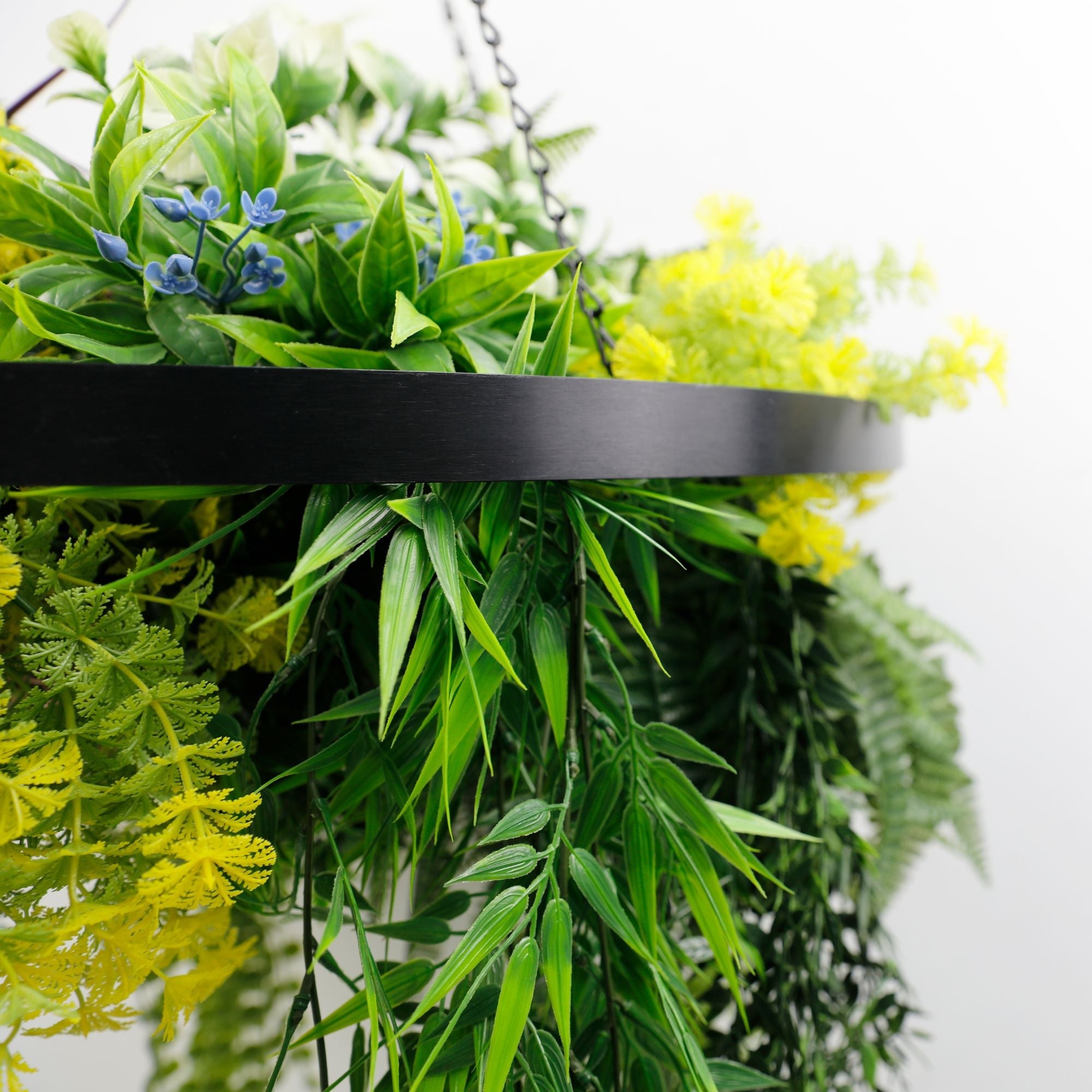 Artificial hanging plant chandelier with tropical foliage, black ring frame, UV resistant draping stems for indoor or outdoor decor.