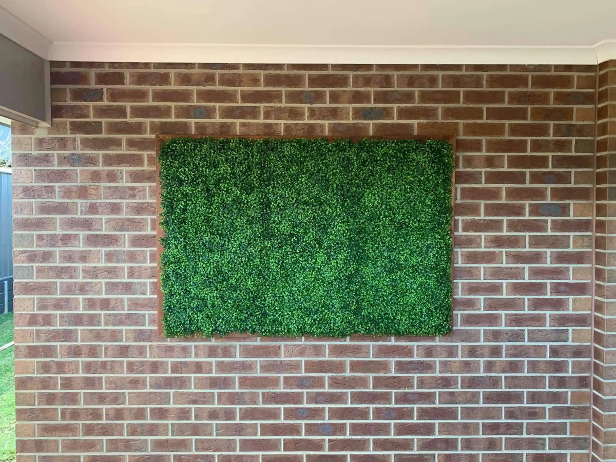 Artificial boxwood hedge panels from Designer Plants USA, 40x40 inch vertical garden green wall on brick wall, UV resistant, commercial grade.