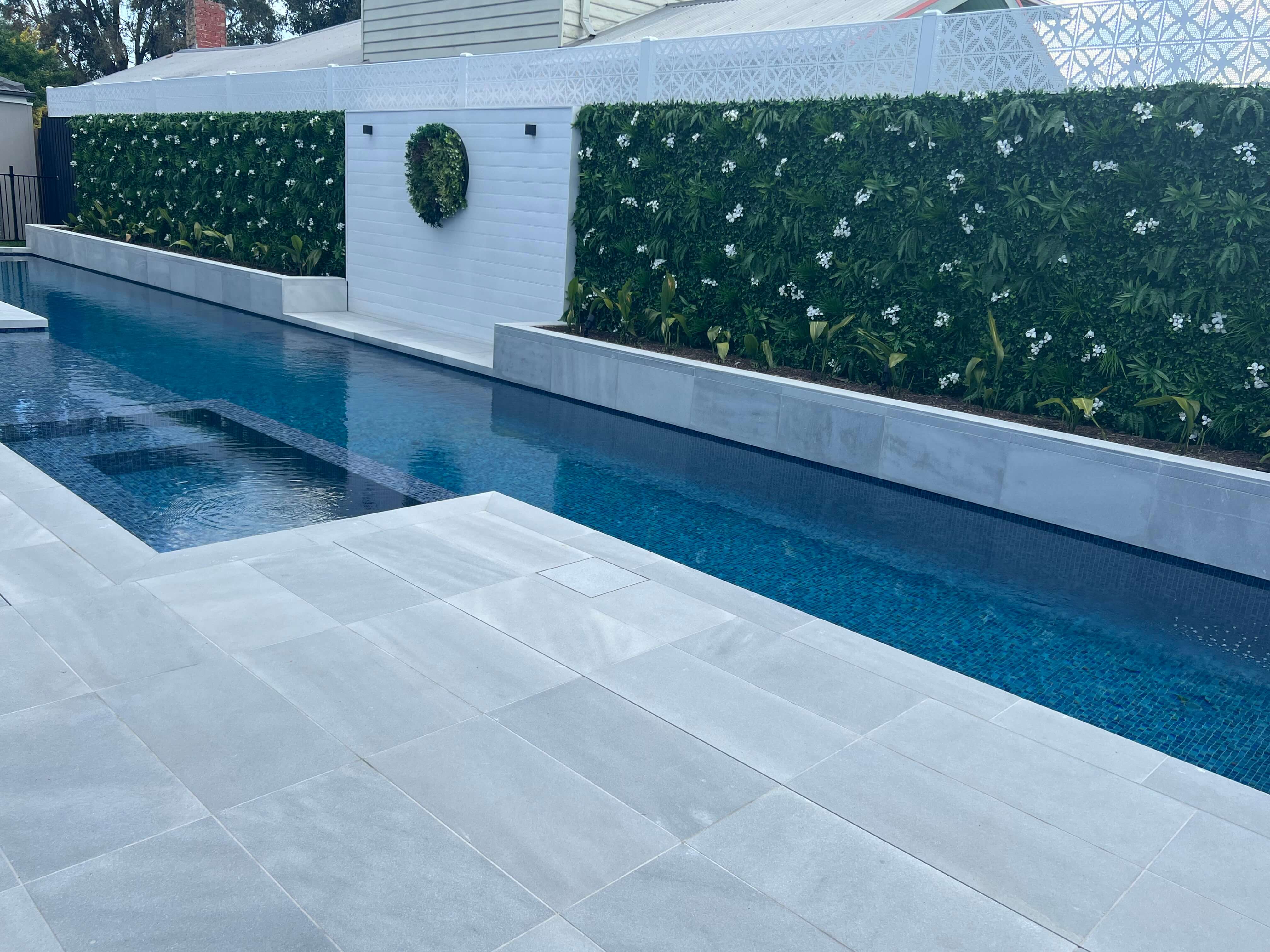 Small sample of Designer Plants USA Snowy White vertical garden panel with artificial flowers, green wall, and poolside setting.
