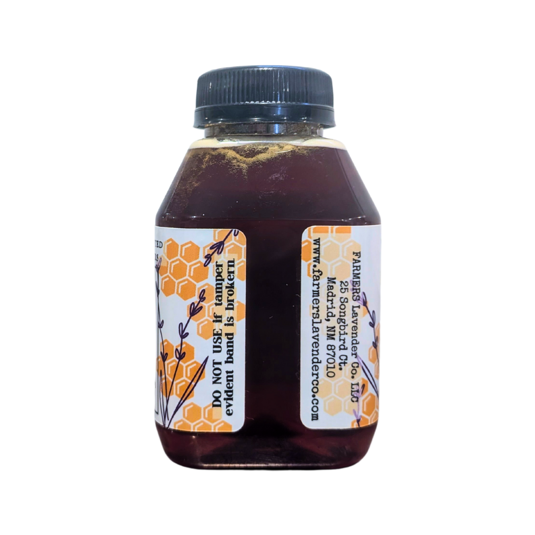 Jar of Lavender Infused Honey from FARMERS Lavender Co. with a golden honey color and fresh lavender flowers beside it.