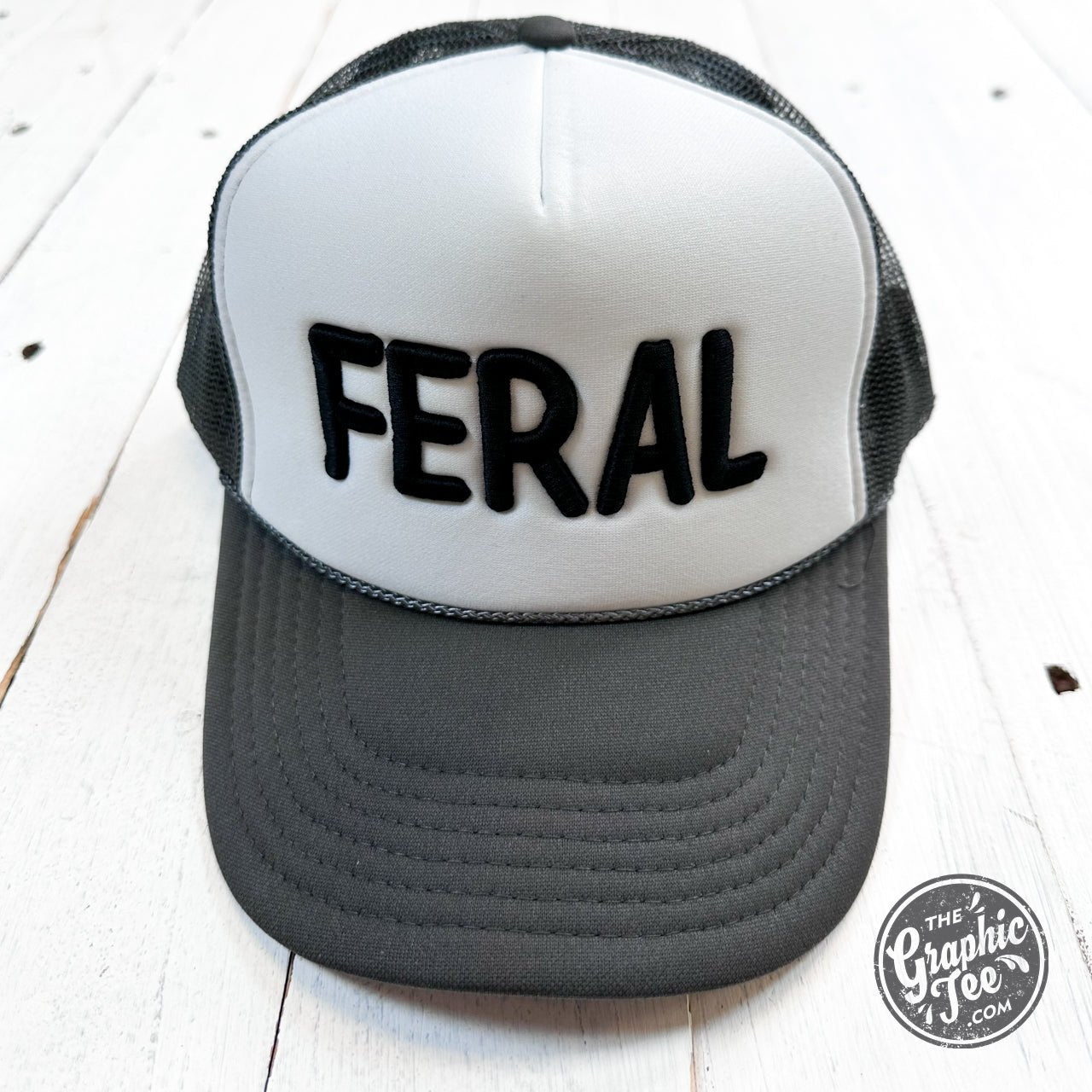 Embroidered Feral design on The Graphic Tee trucker cap, featuring a structured cap with mesh back and adjustable strap.