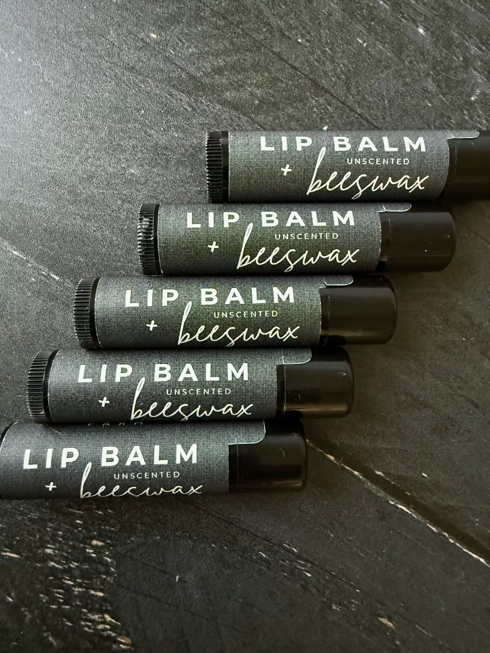Unlabeled beeswax lip balm from Five Oaks Farm, natural and unscented, in a small tin container.