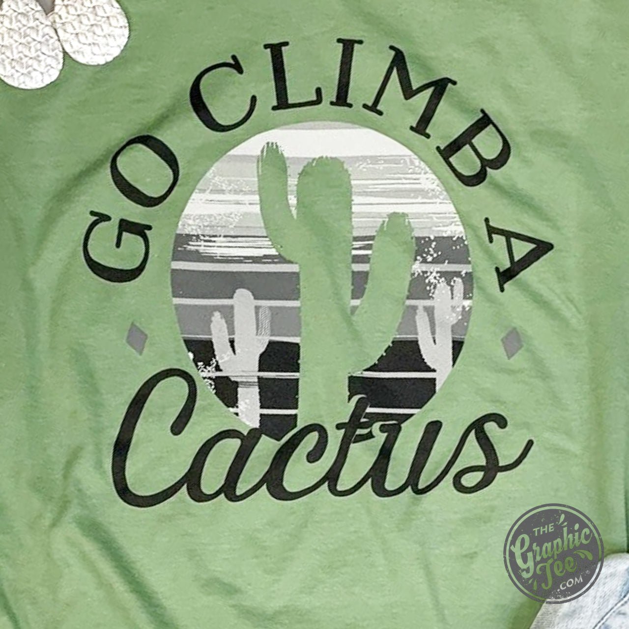 The Graphic Tee Go Climb A Cactus short sleeve graphic tee featuring a cactus design on soft fabric.