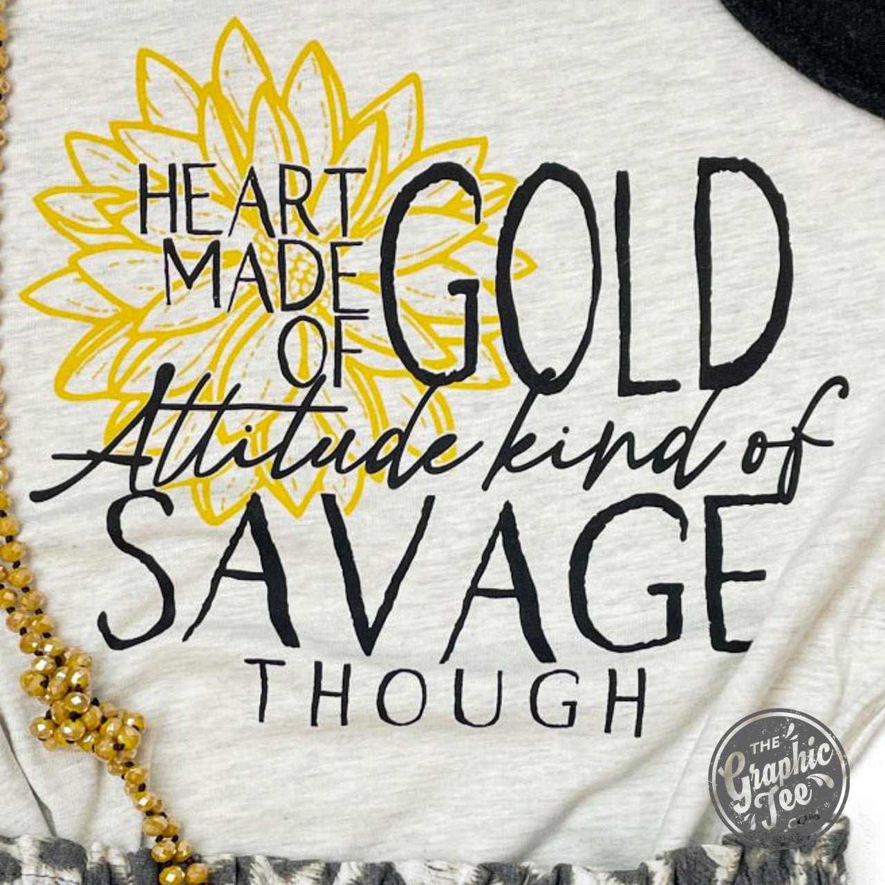 Gold heart graphic on The Graphic Tee's attitude-inspired SS graphic tee, showcasing bold, stylish design for casual wear.