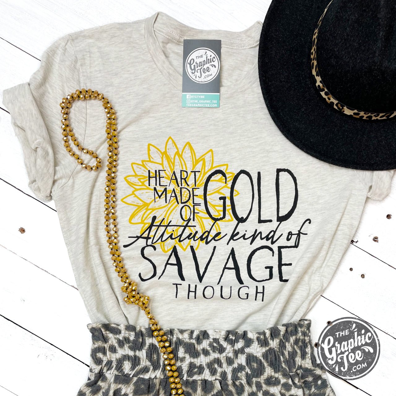 Gold heart graphic on The Graphic Tee's attitude-inspired SS graphic tee, showcasing a bold, stylish design.
