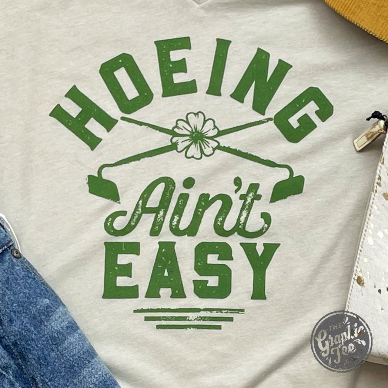 White V-neck gardening T-shirt from The Graphic Tee featuring a humorous "Hoeing Ain't Easy" graphic design.