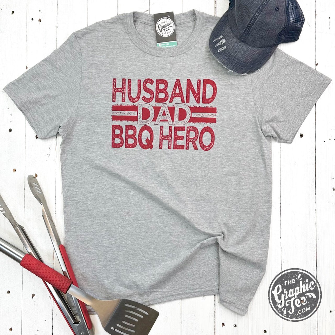 Unisex short sleeve graphic tee featuring a husband and dad BBQ hero design by The Graphic Tee.