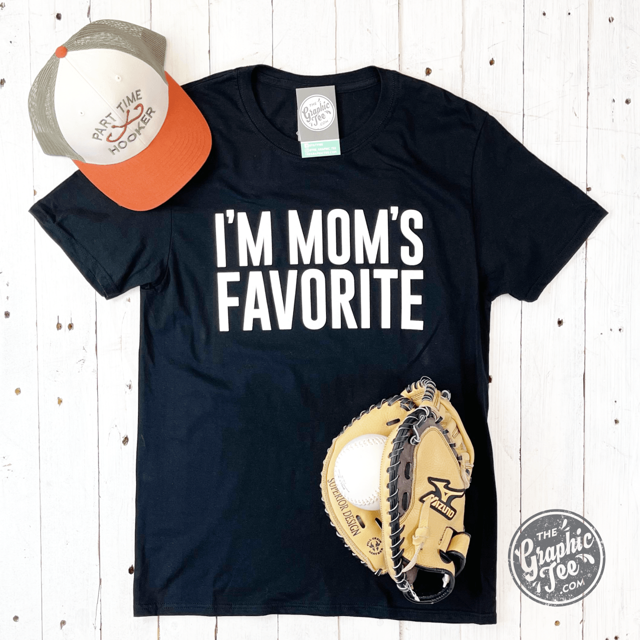 Black graphic t-shirt from The Graphic Tee with "I'm Mom's Favorite" slogan, short sleeve design, casual style.