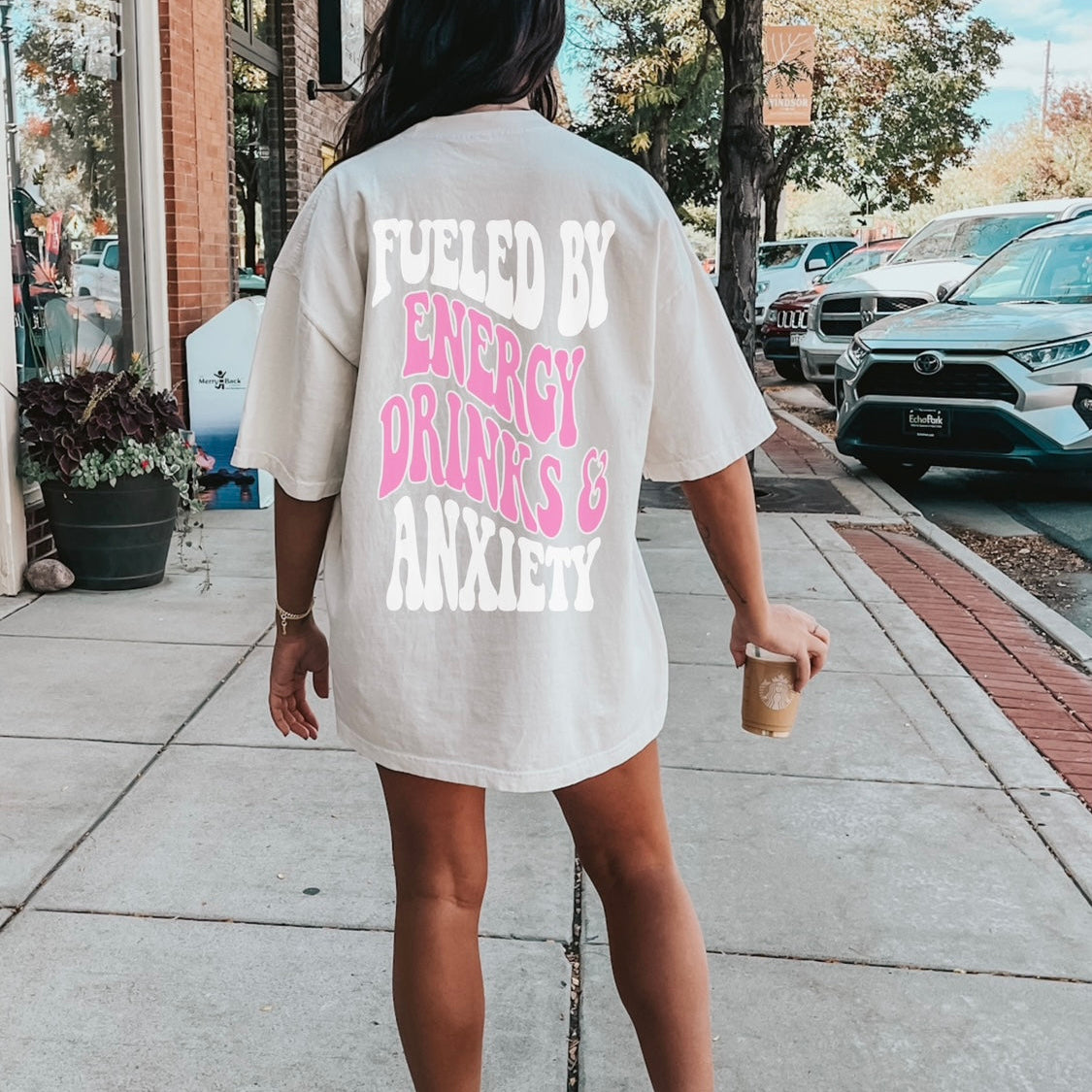 Black graphic tee from Shop Karma Tees featuring "Fueled By Energy Drinks and Anxiety" text and vibrant design on front.