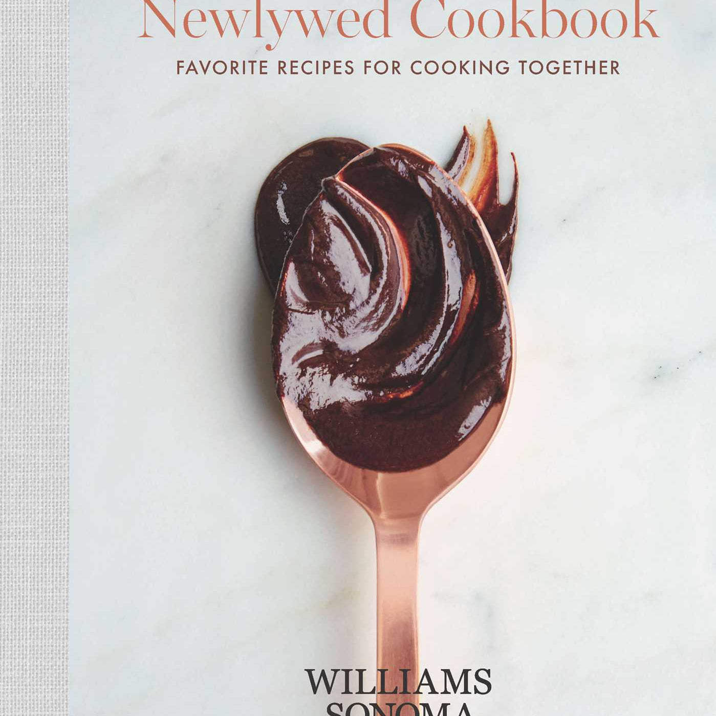 Hardcover copy of The Newlywed Cookbook by Insight Editions, featuring a cozy kitchen scene with recipe pages and cooking utensils.