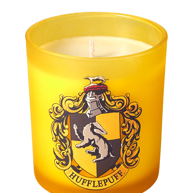 Hufflepuff scented glass candle from Harry Potter featuring a Hufflepuff crest design on a clear glass container.