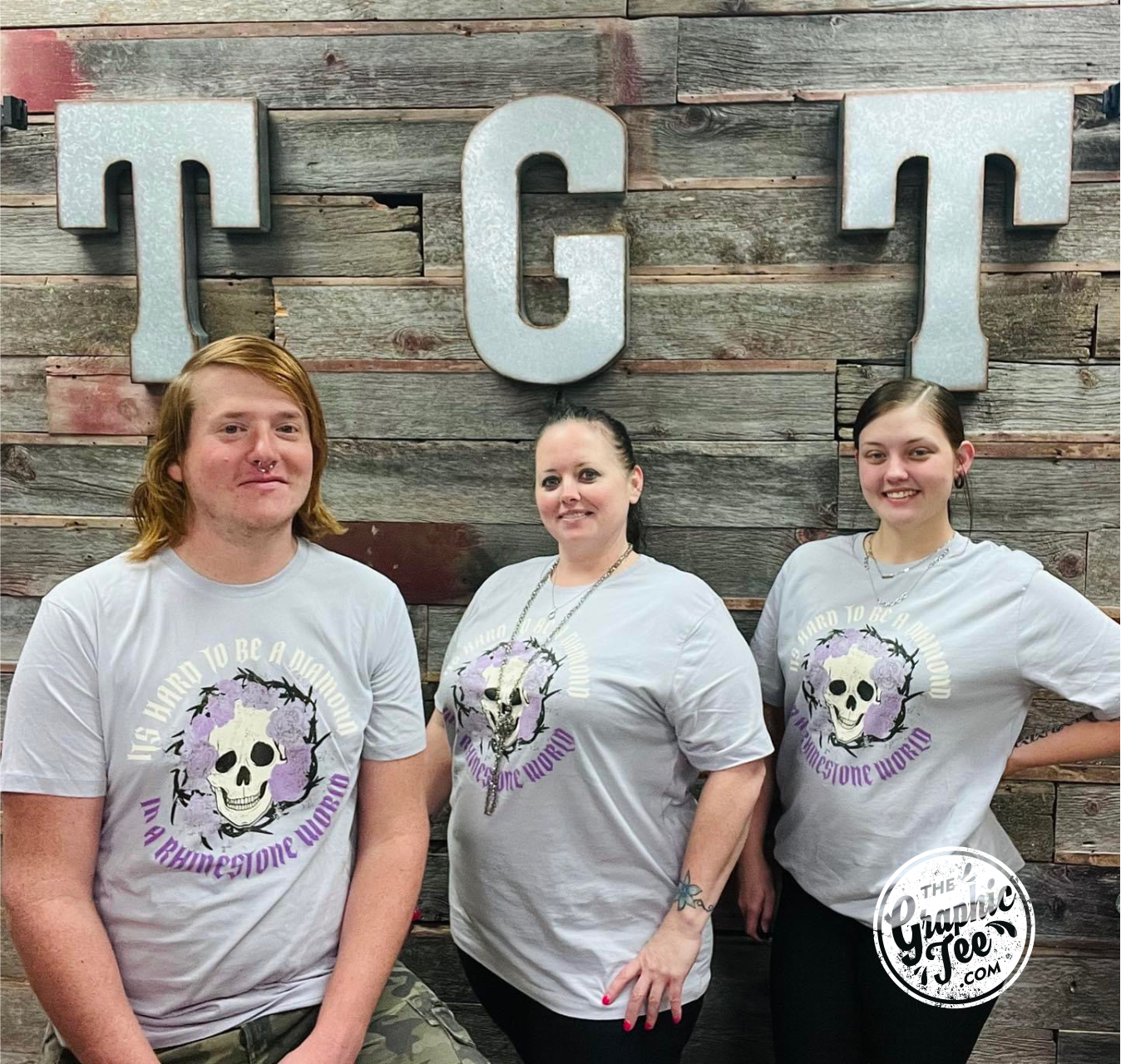 Lilac short sleeve graphic tee from The Graphic Tee featuring the phrase "It's Hard to Be A Diamond in A Rhinestone World" on a stylish design.